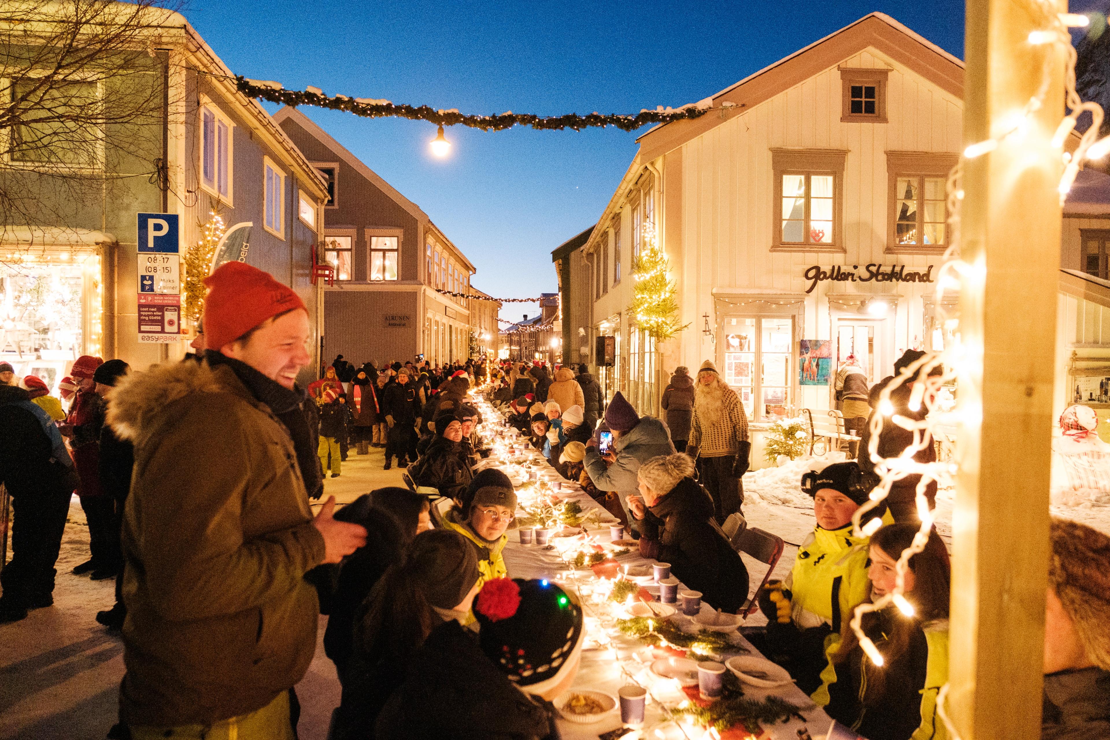 People enjoying porrige with a long table outside.