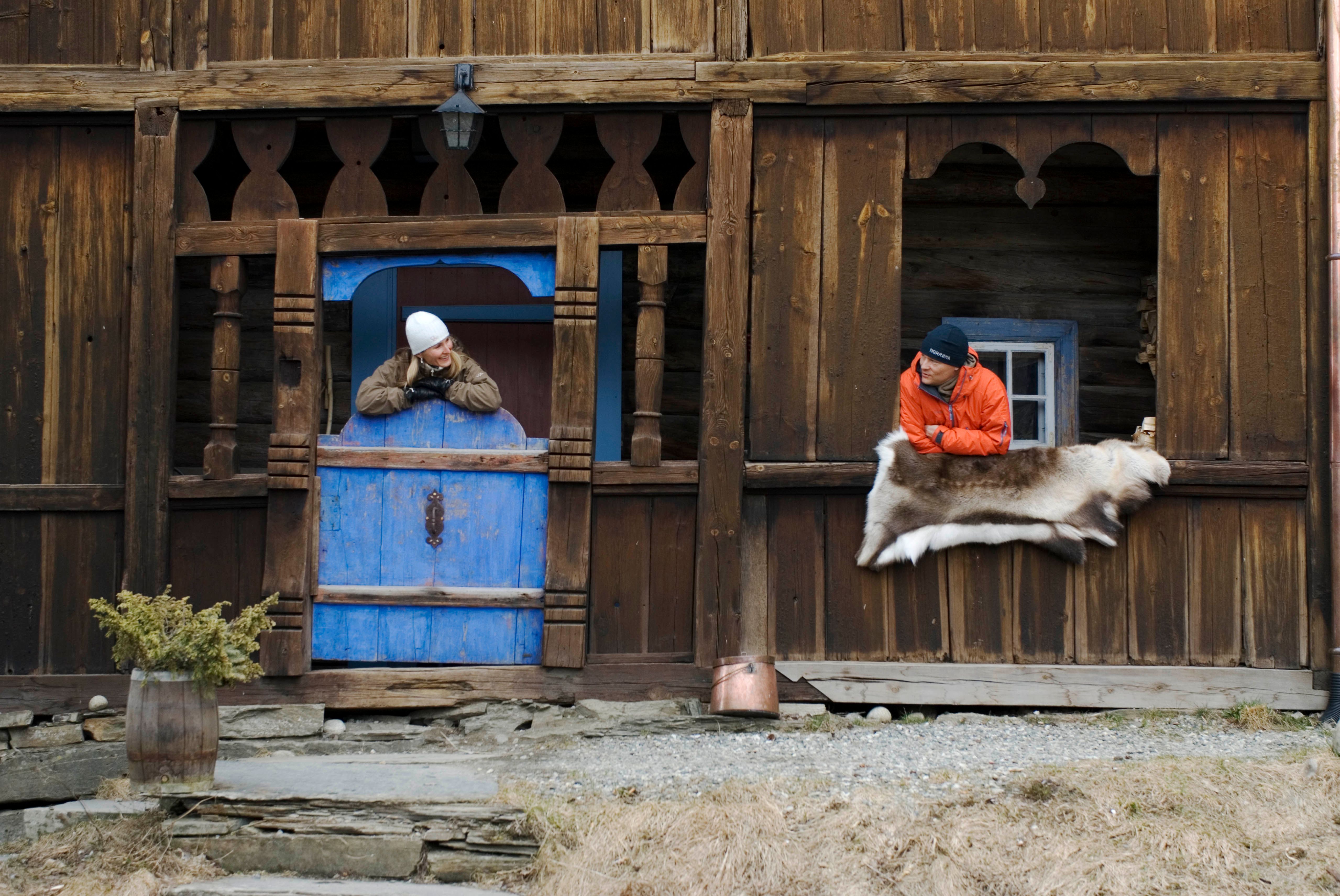 Two people hanging out of windows at the Per Gynt gården in Vinstra, Eastern Norway
