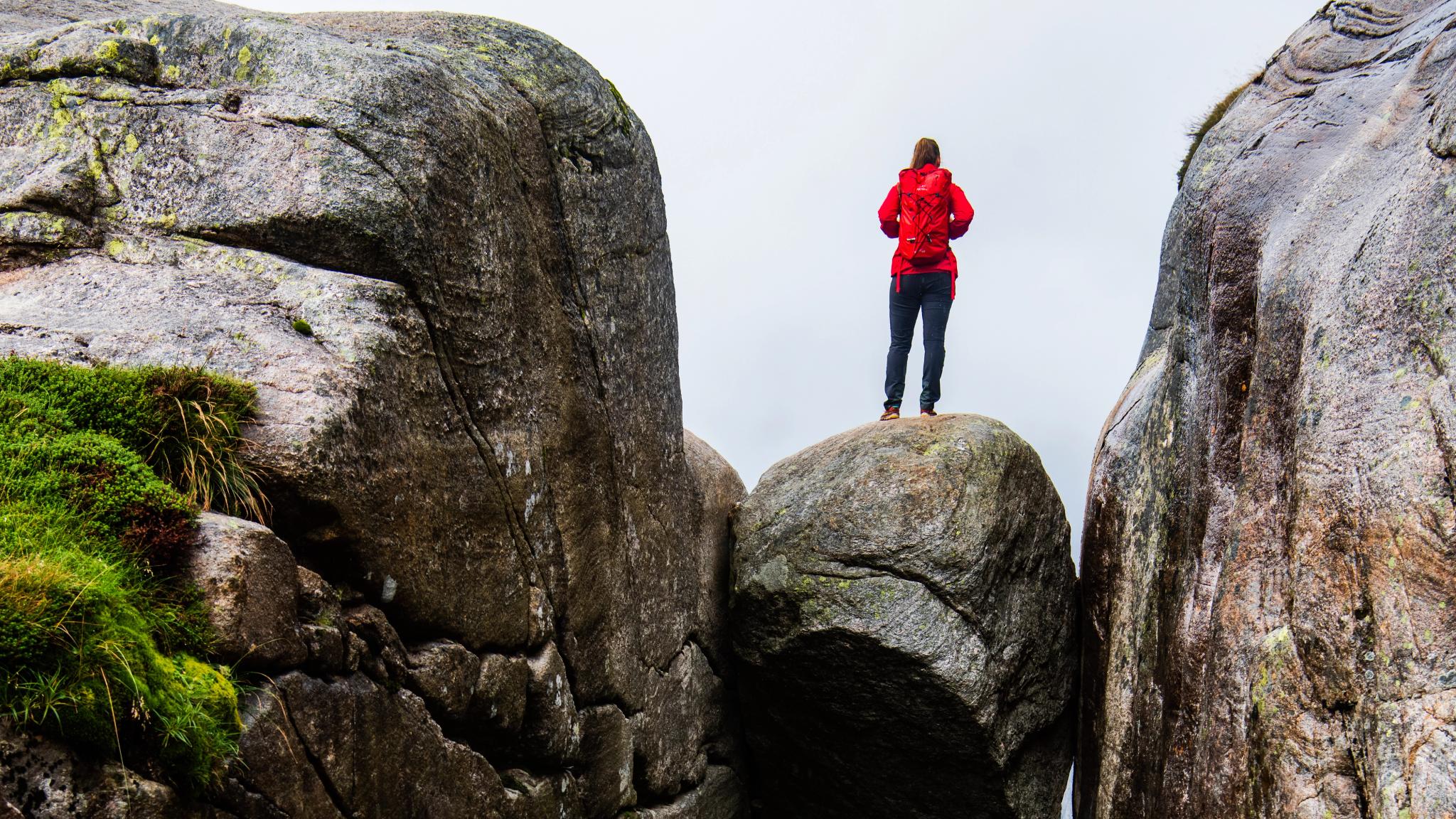 A woman standing on the famous Kjeragbolten rock on Mount Kjerag in Ryfylke, Fjord Norway