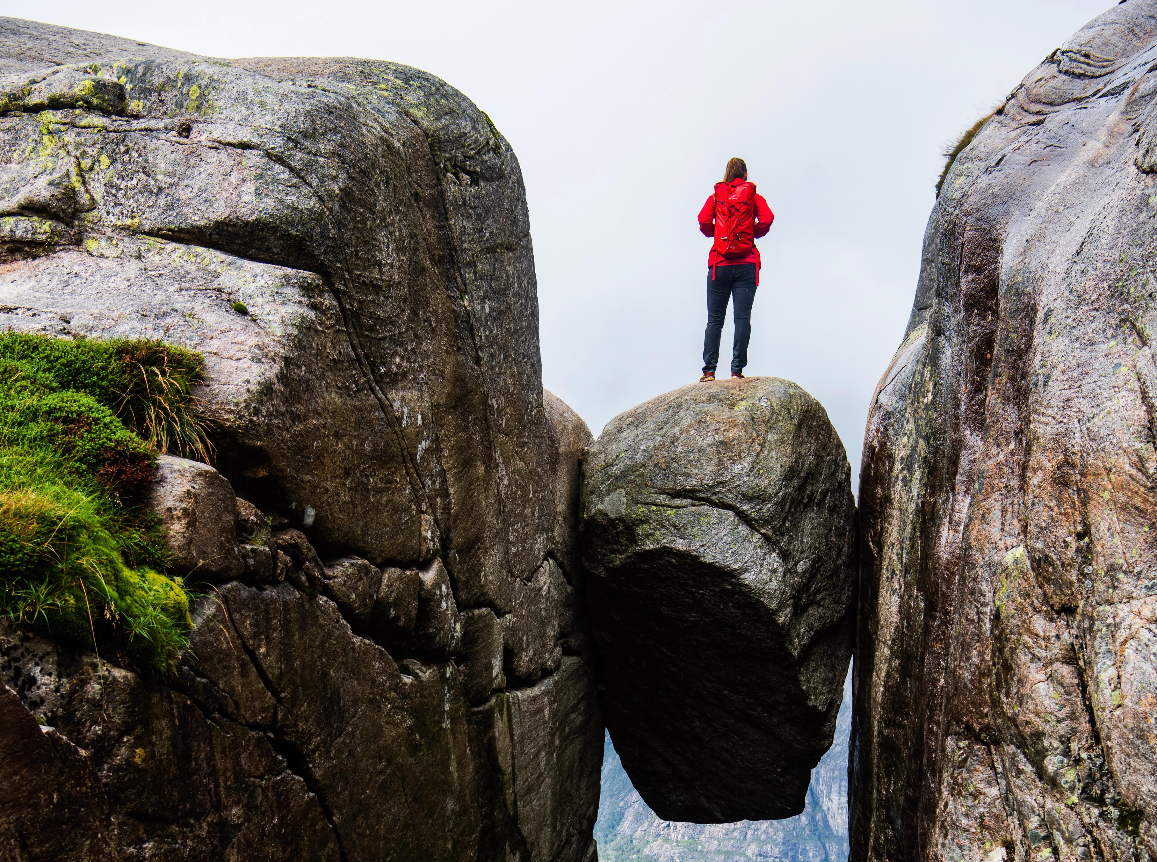 A woman standing on the famous Kjeragbolten rock on Mount Kjerag in Ryfylke, Fjord Norway