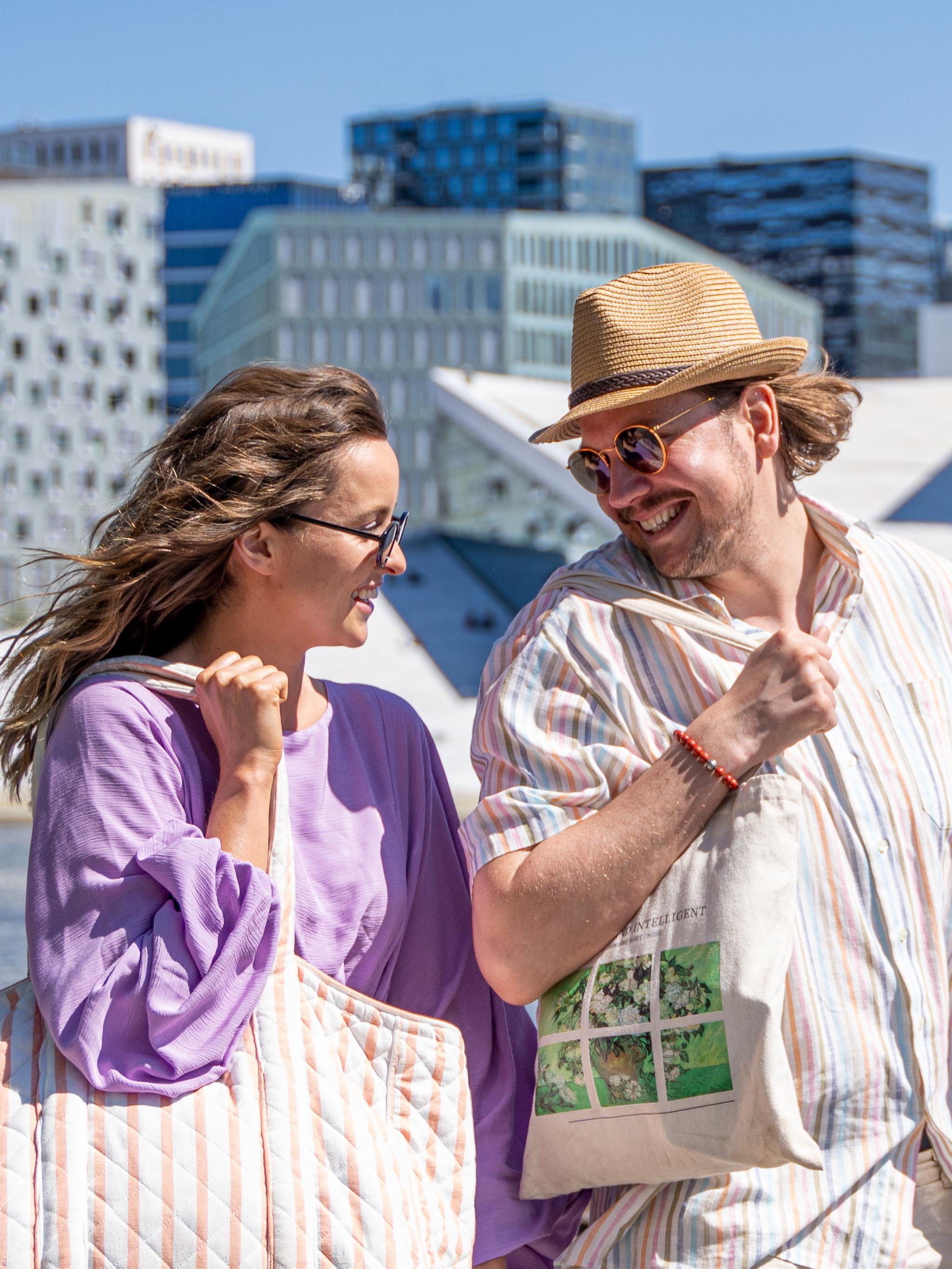 Kvinne og mann vandrer rundt Oslo's havnepromenade med Operahuset i bakgrunnen