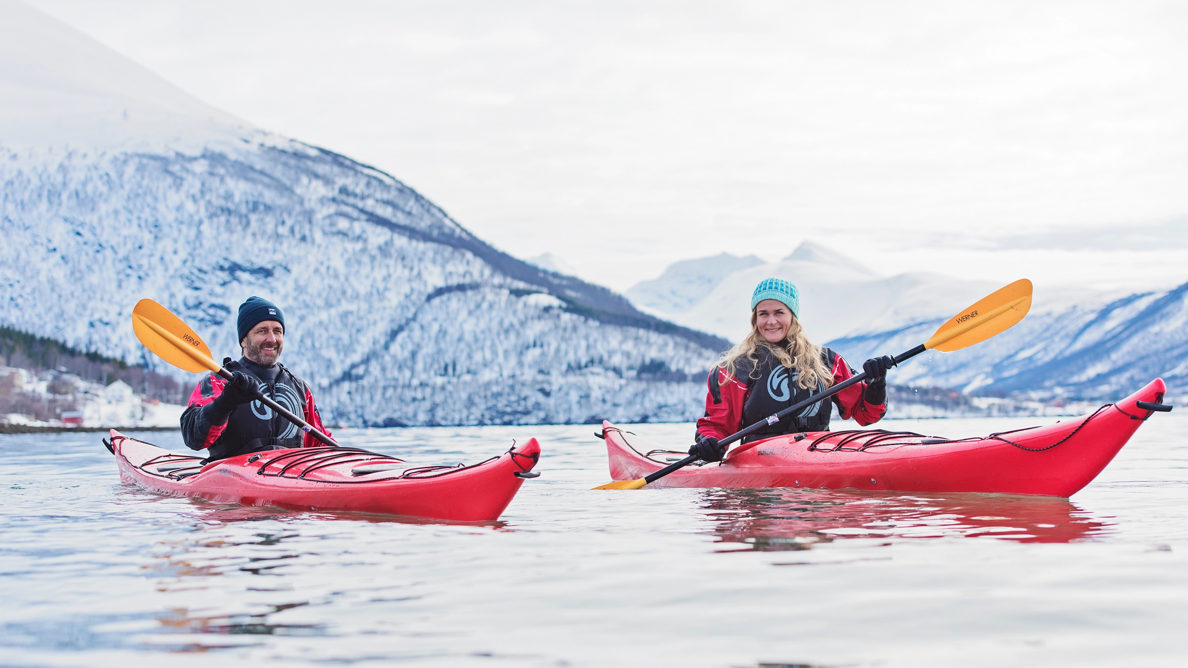 Two people on a Hurtigruten coastal expedition kayaking in the winter in Norway