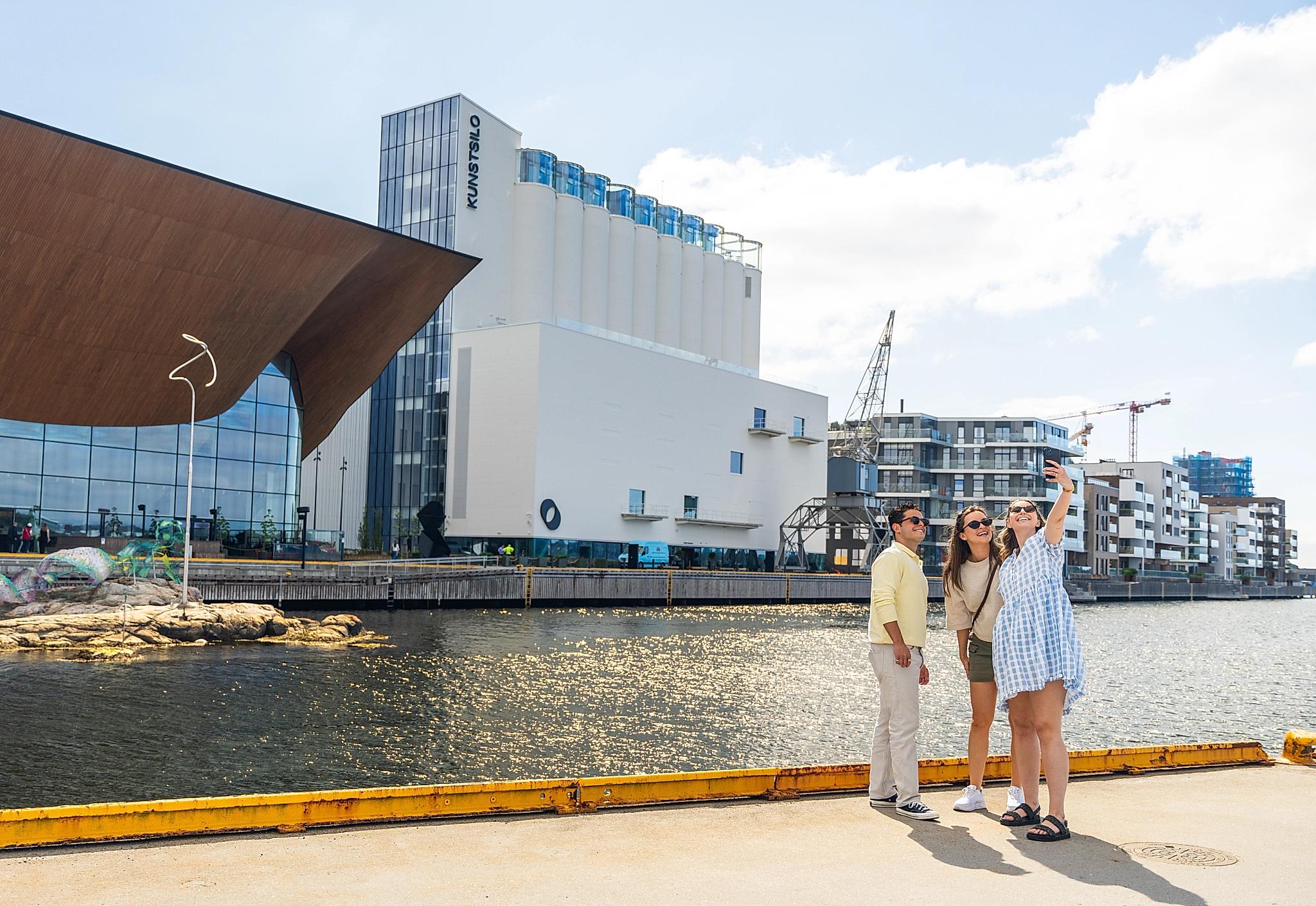 Three people taking a selfie in front of Kilden and Kunstsilo in Kristiansand