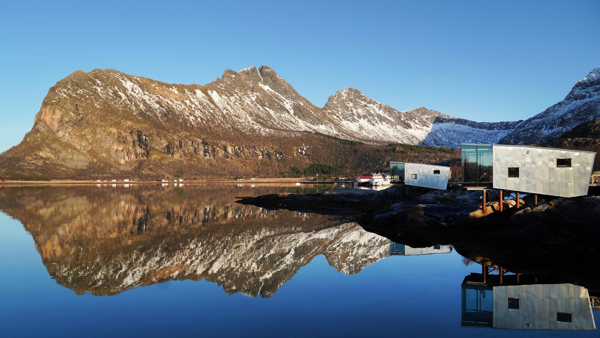 Cabins by the sea and a mountain backdrop.