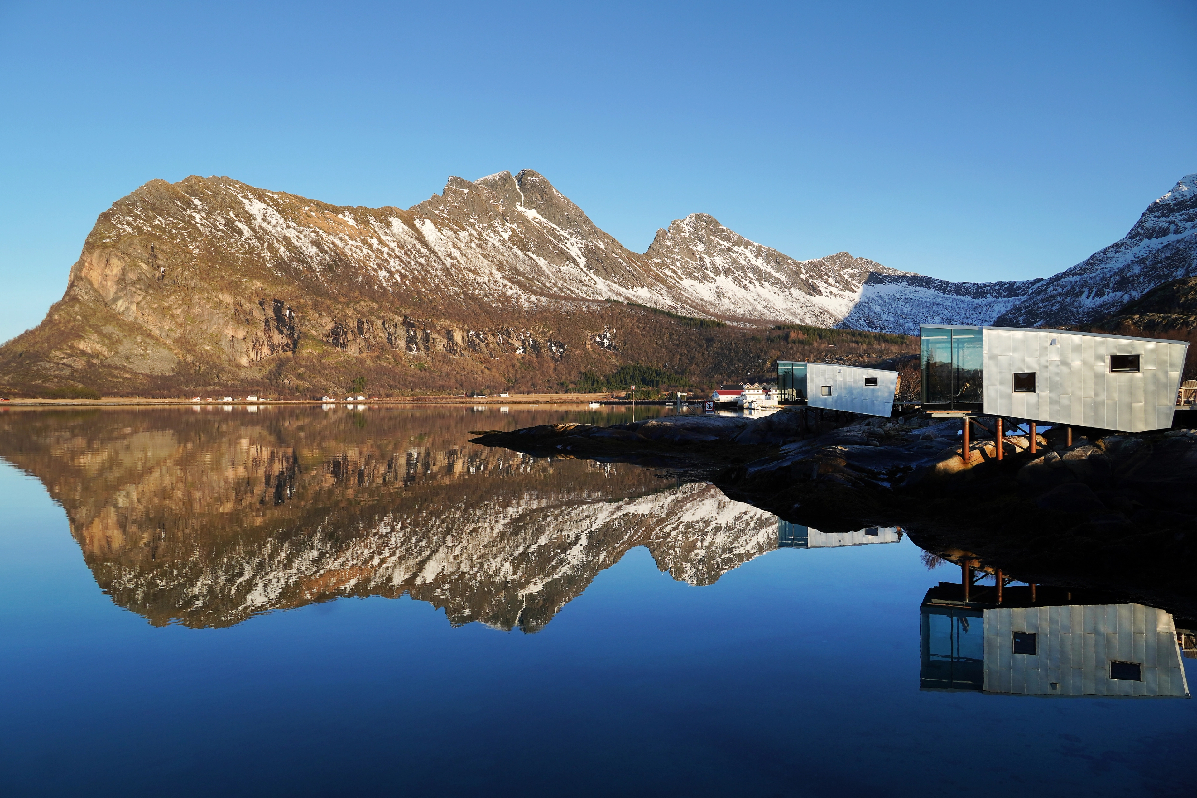 Cabins by the sea and a mountain backdrop.