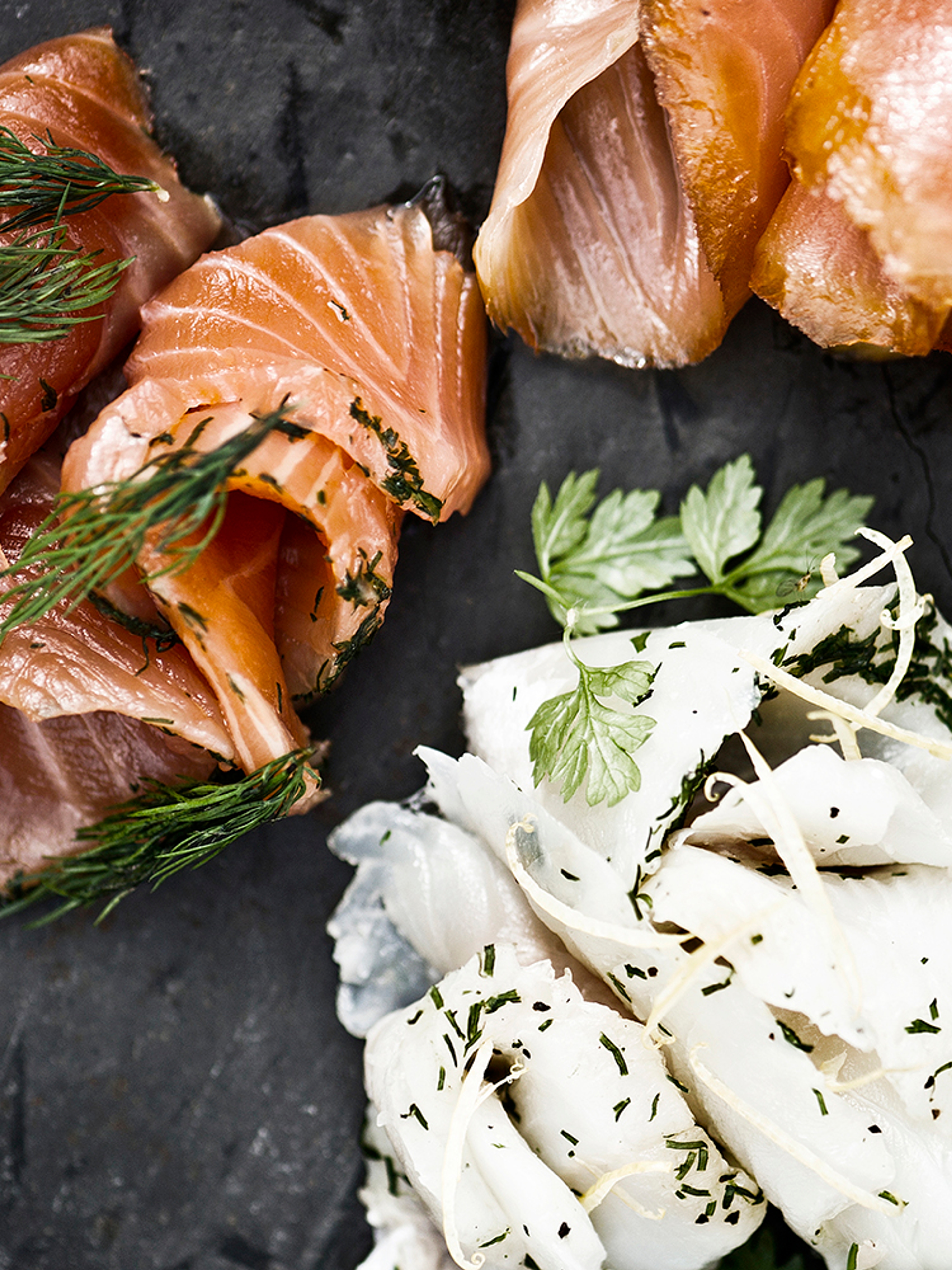 A stone platter with smoked salmon and other food