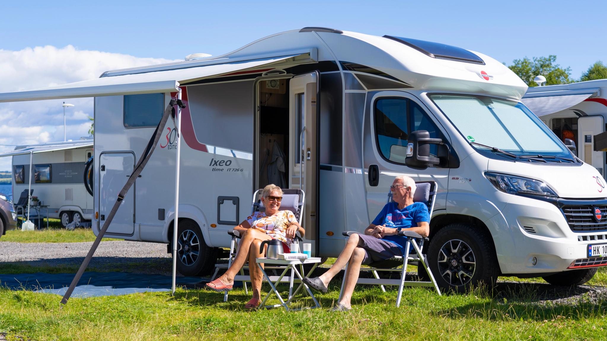 Two people in front of a motorhome on camping