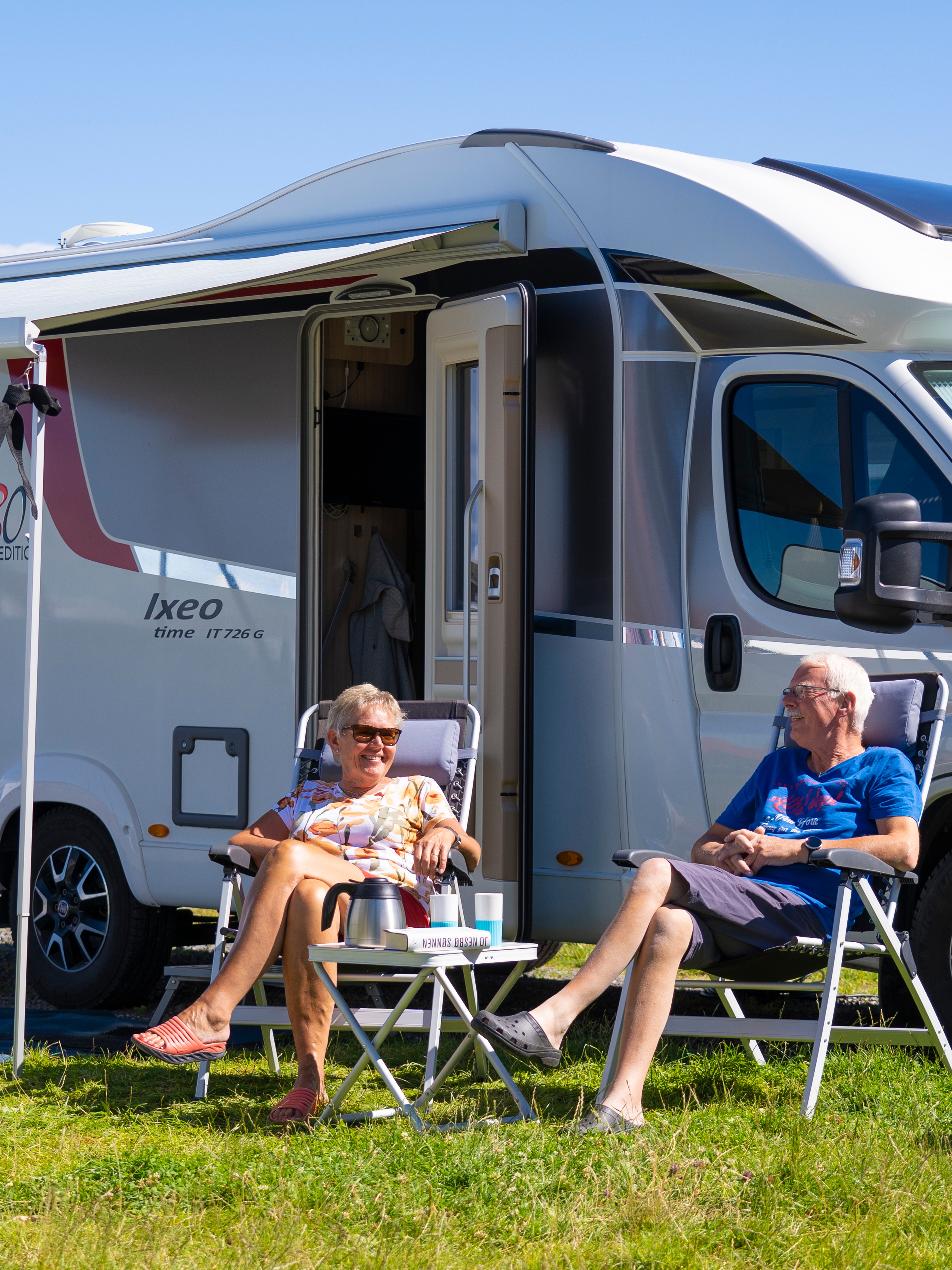 Two people in front of a motorhome on camping