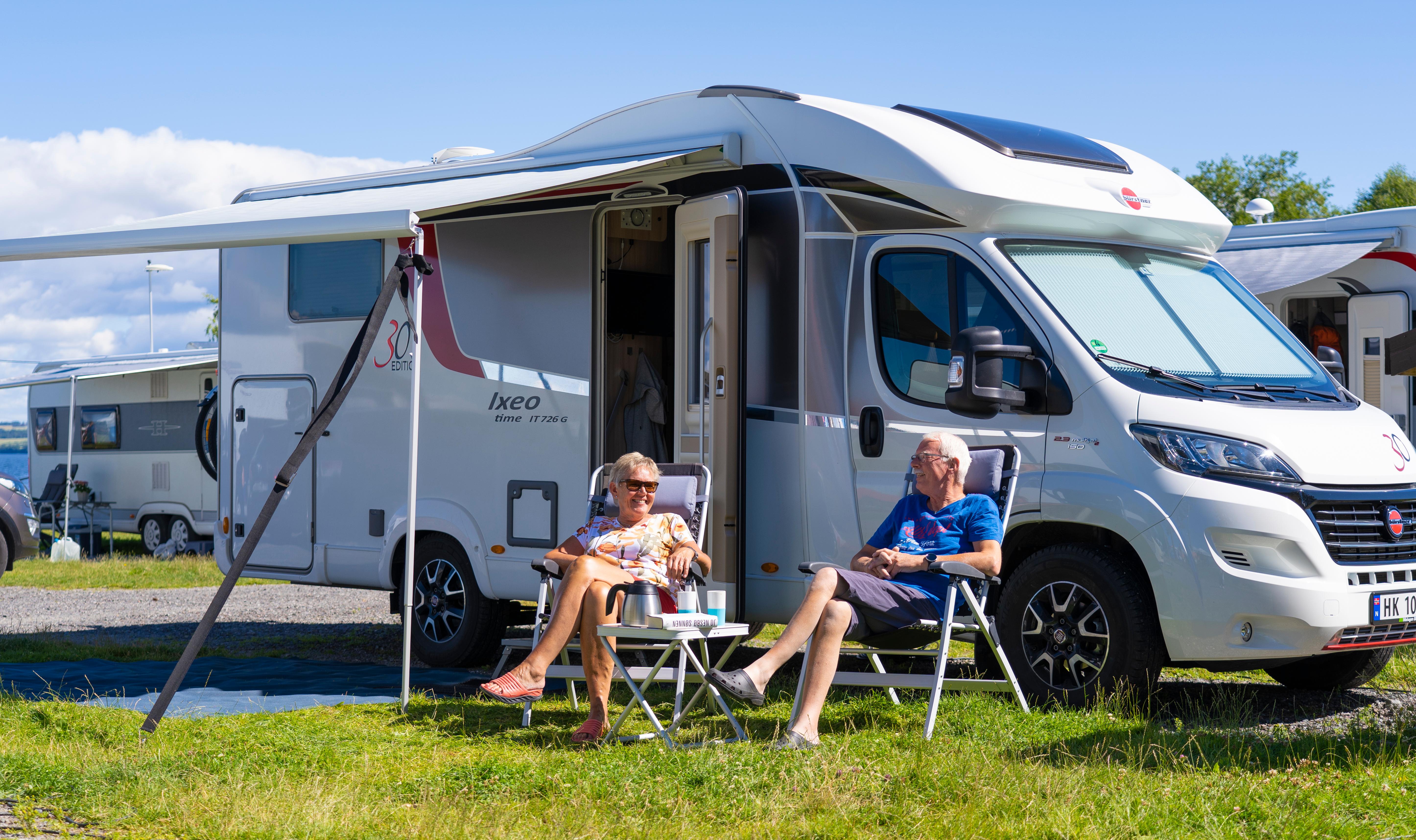 Two people in front of a motorhome on camping