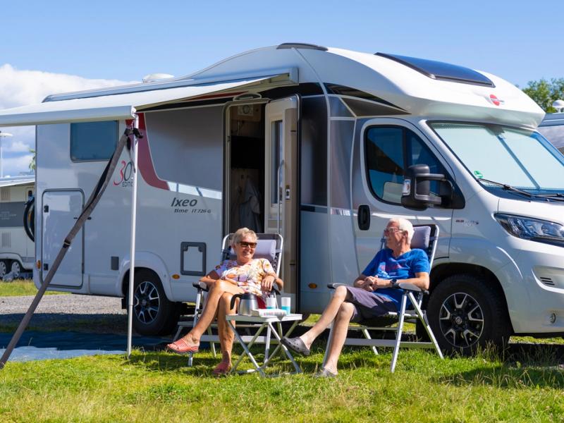 Two people in front of a motorhome on camping
