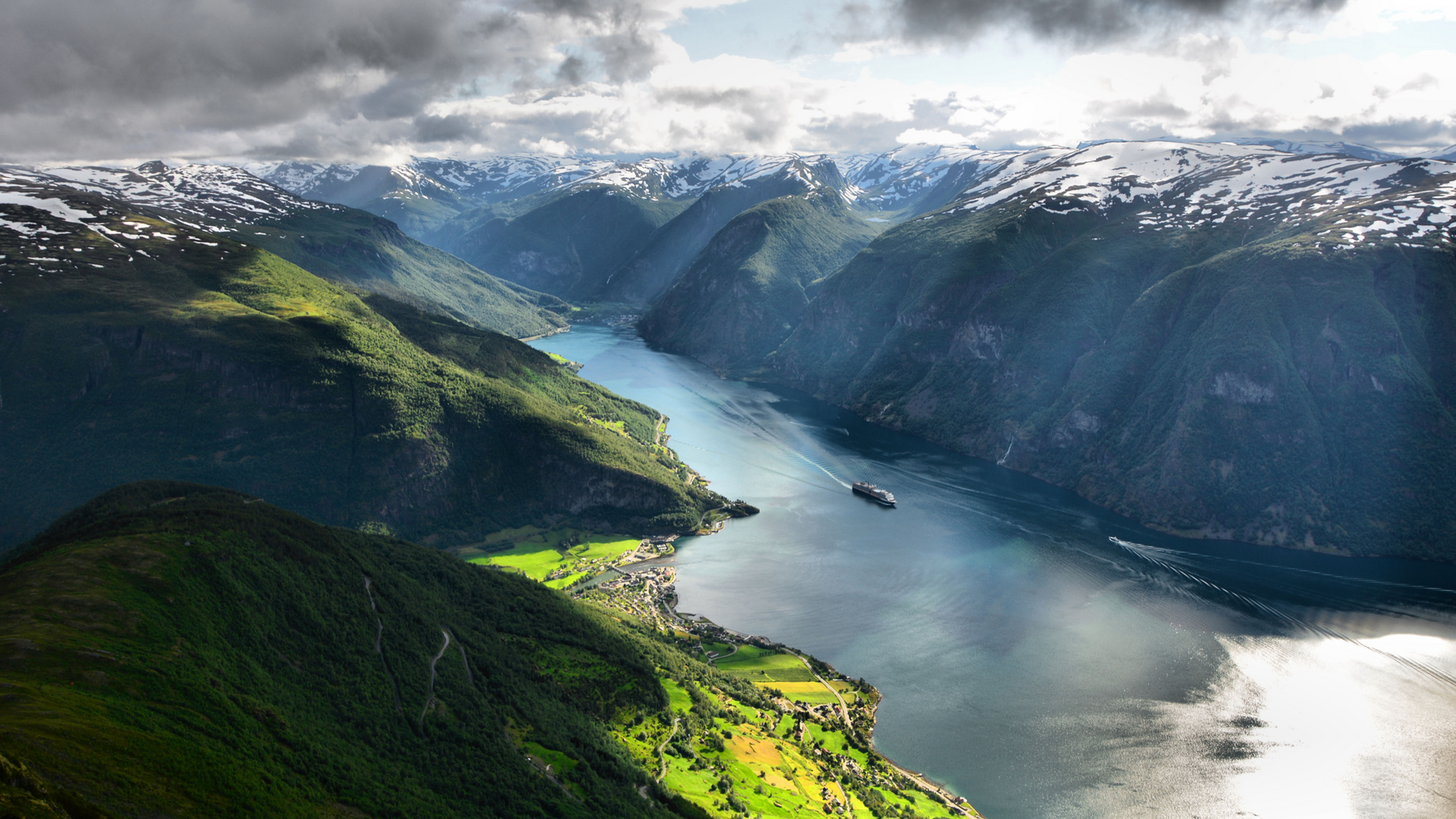 Overview of a green fjord with snowcapped mountains