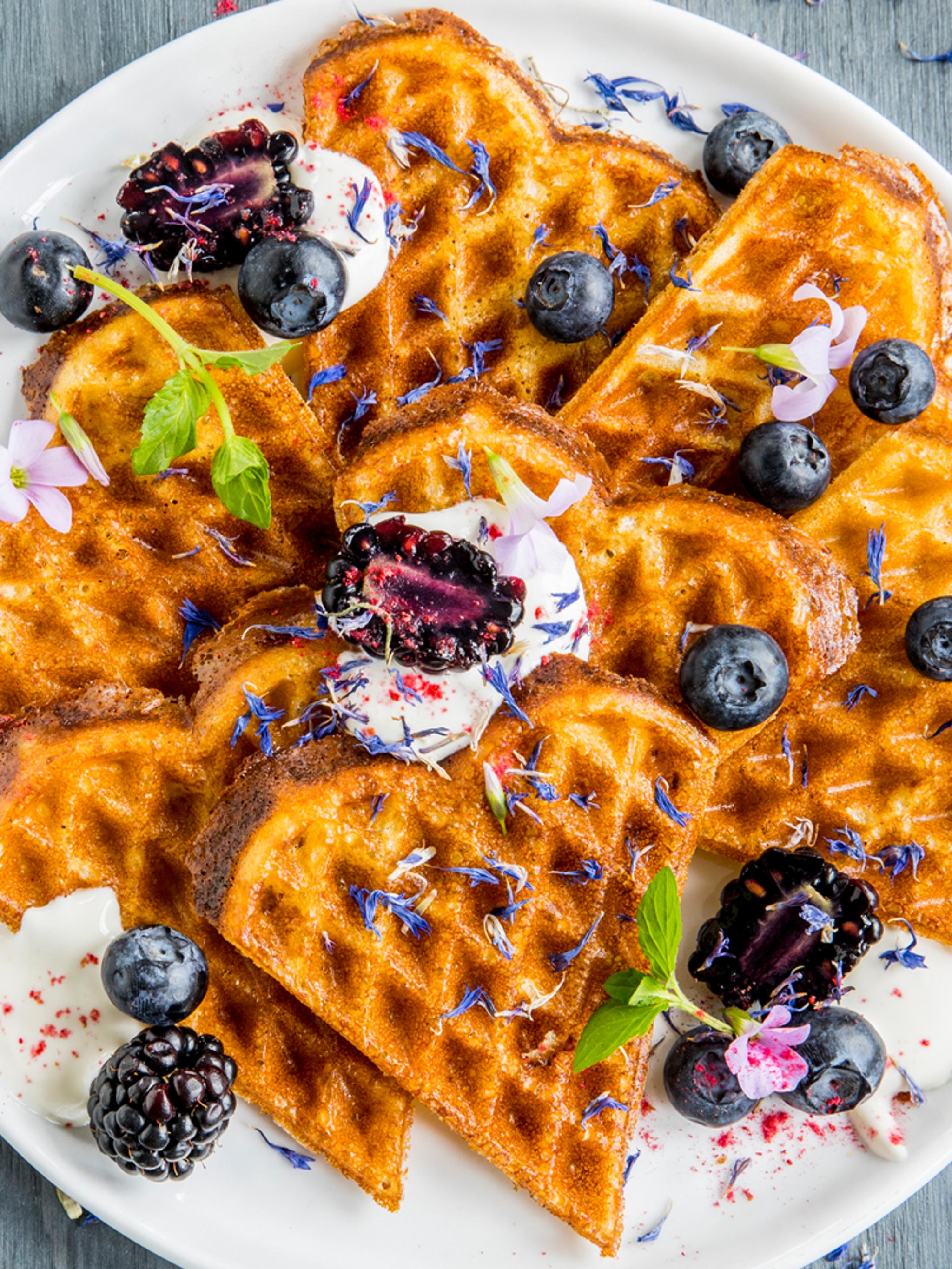 A plate of waffles with sour cream and berries