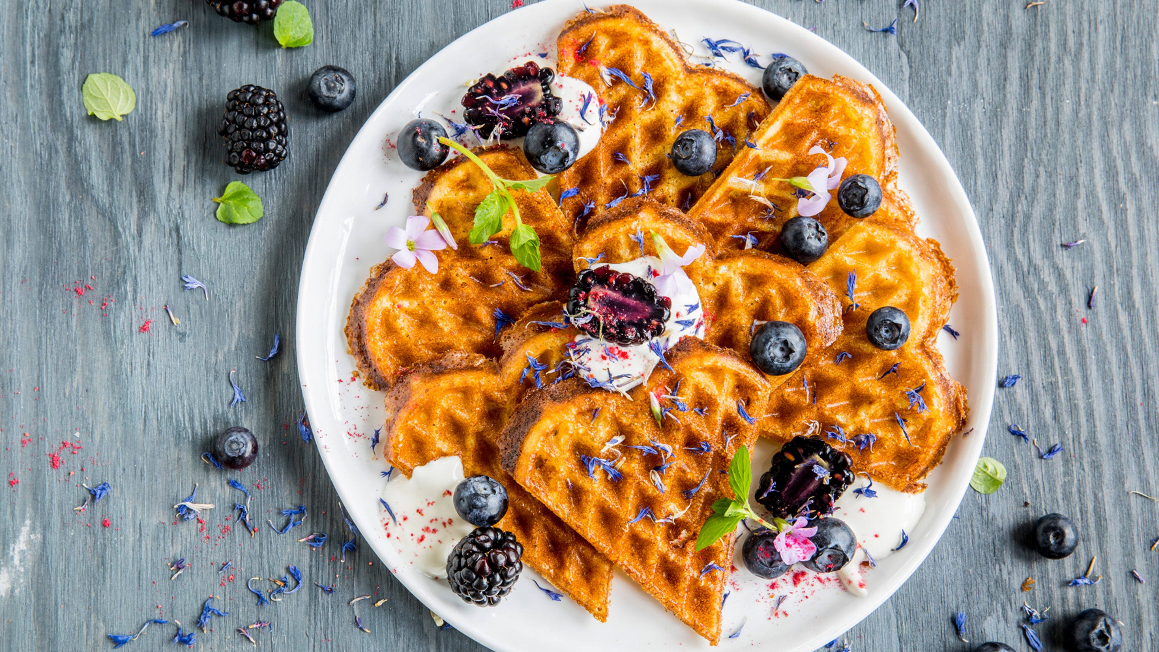 A plate of waffles with sour cream and berries