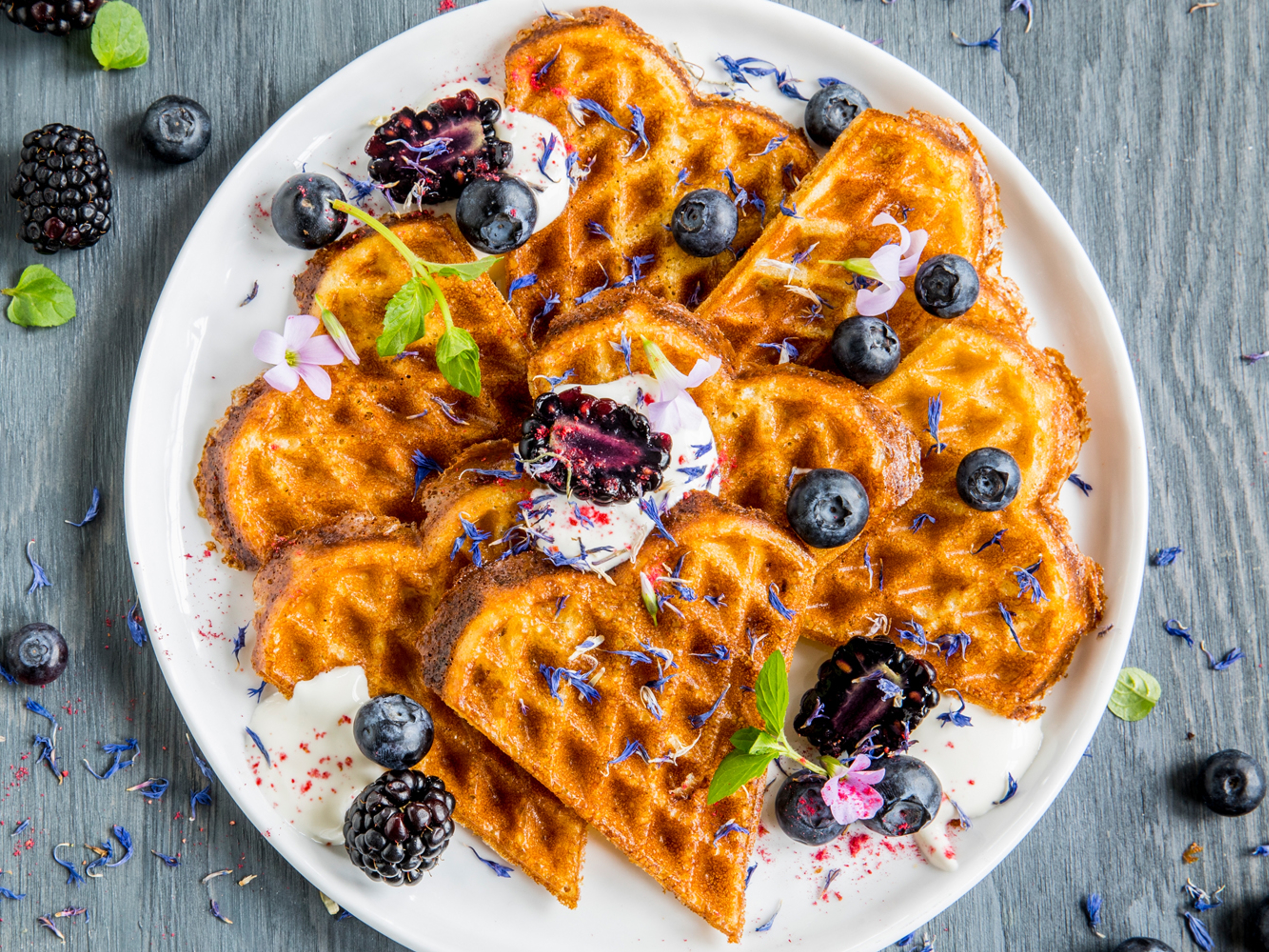 A plate of waffles with sour cream and berries