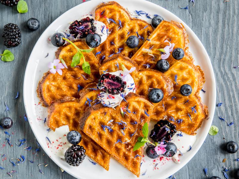 A plate of waffles with sour cream and berries
