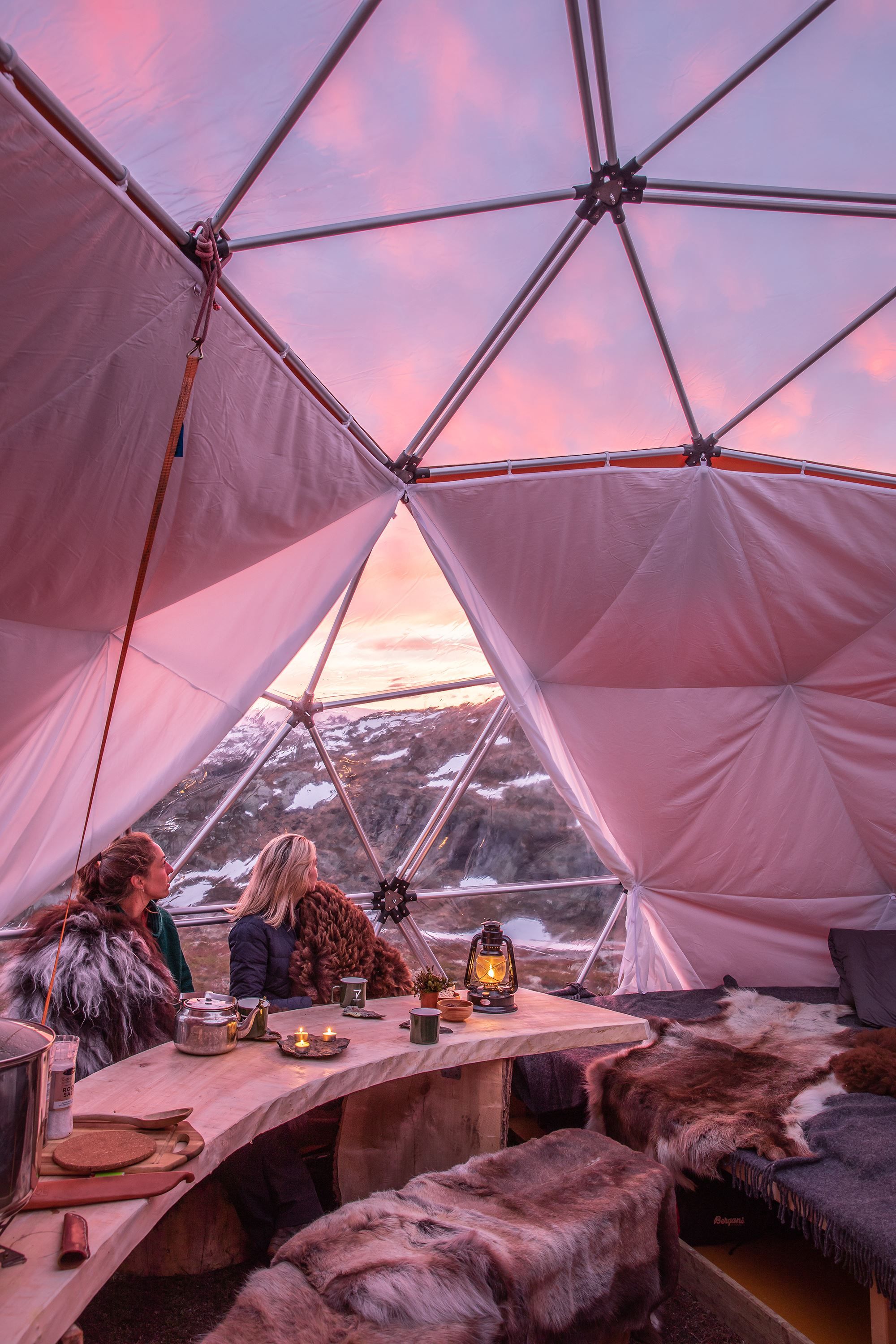 Personer nyder solnedgangen inde fra en dome med glastag