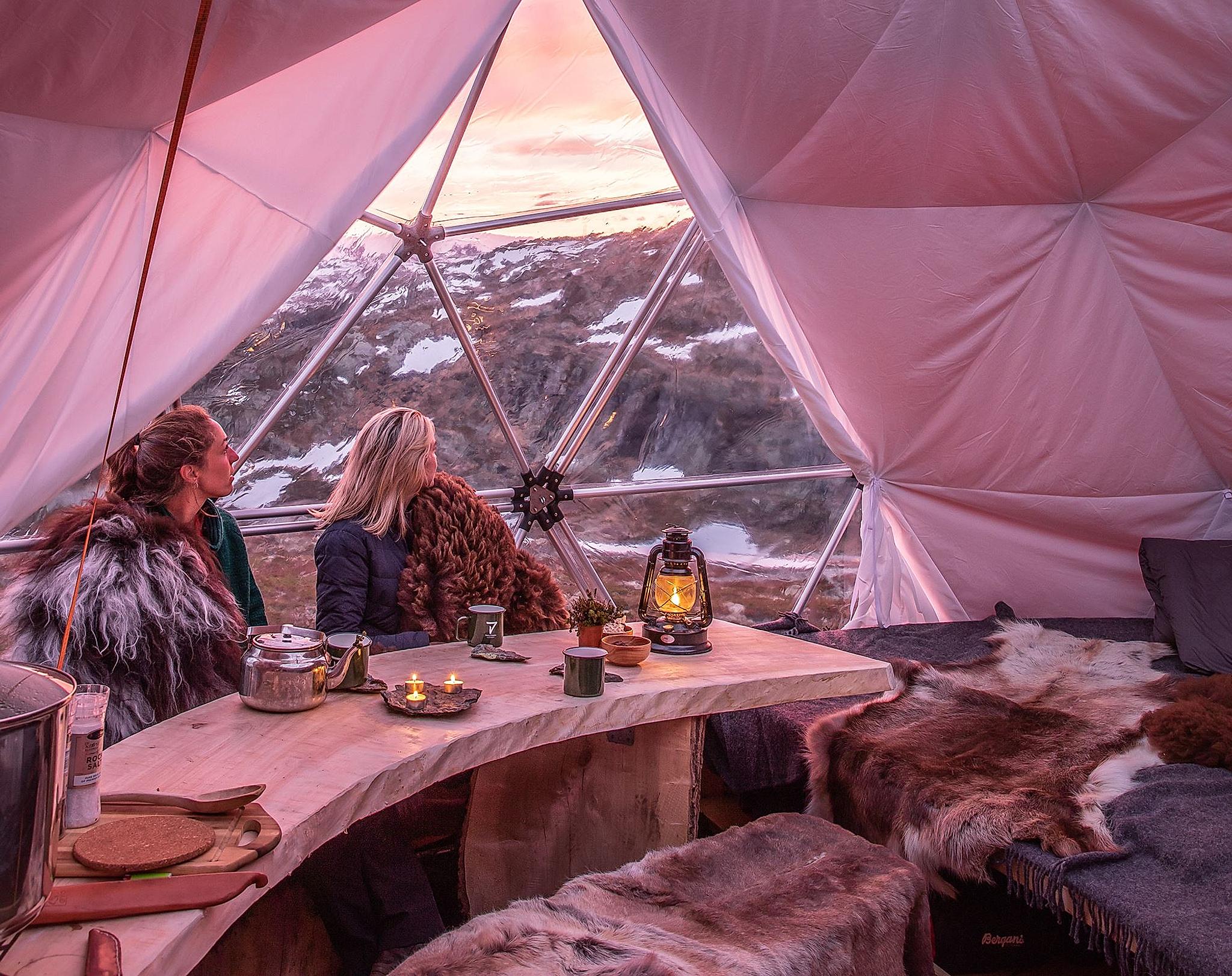 Personer nyder solnedgangen inde fra en dome med glastag