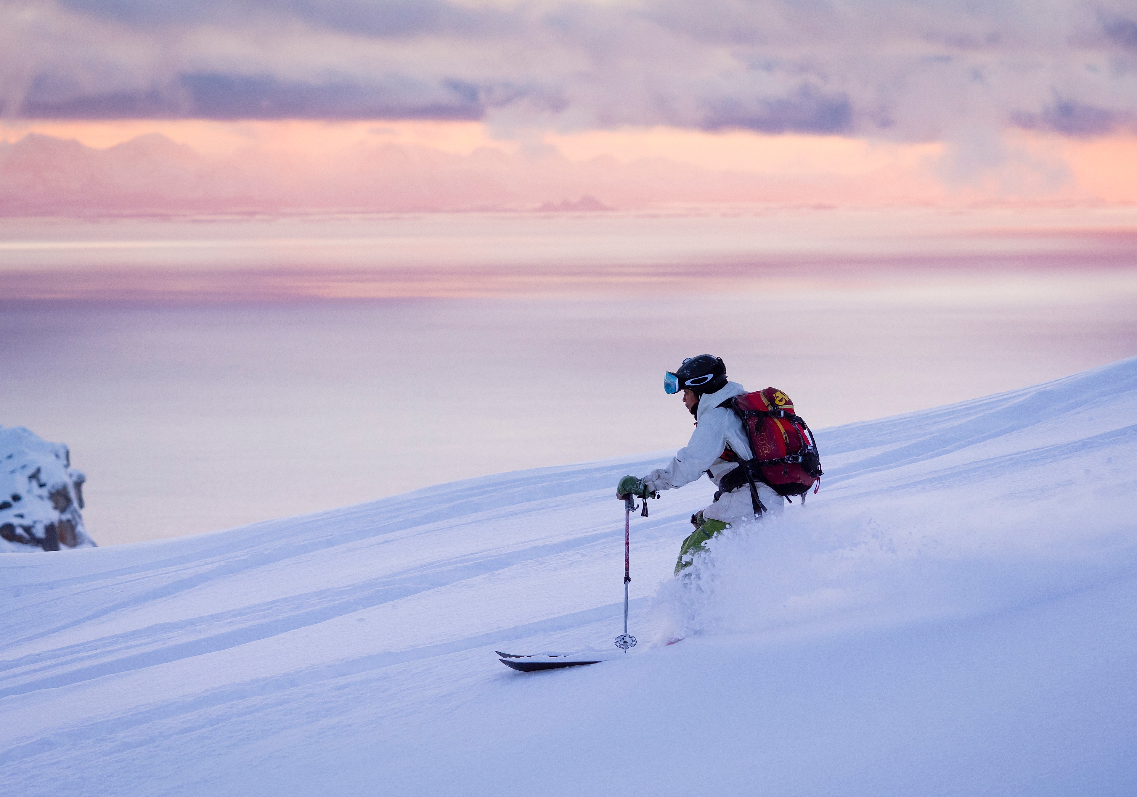 Woman skiing at Småtindan mountain under a pink sky in Lofoten, Northern Norway