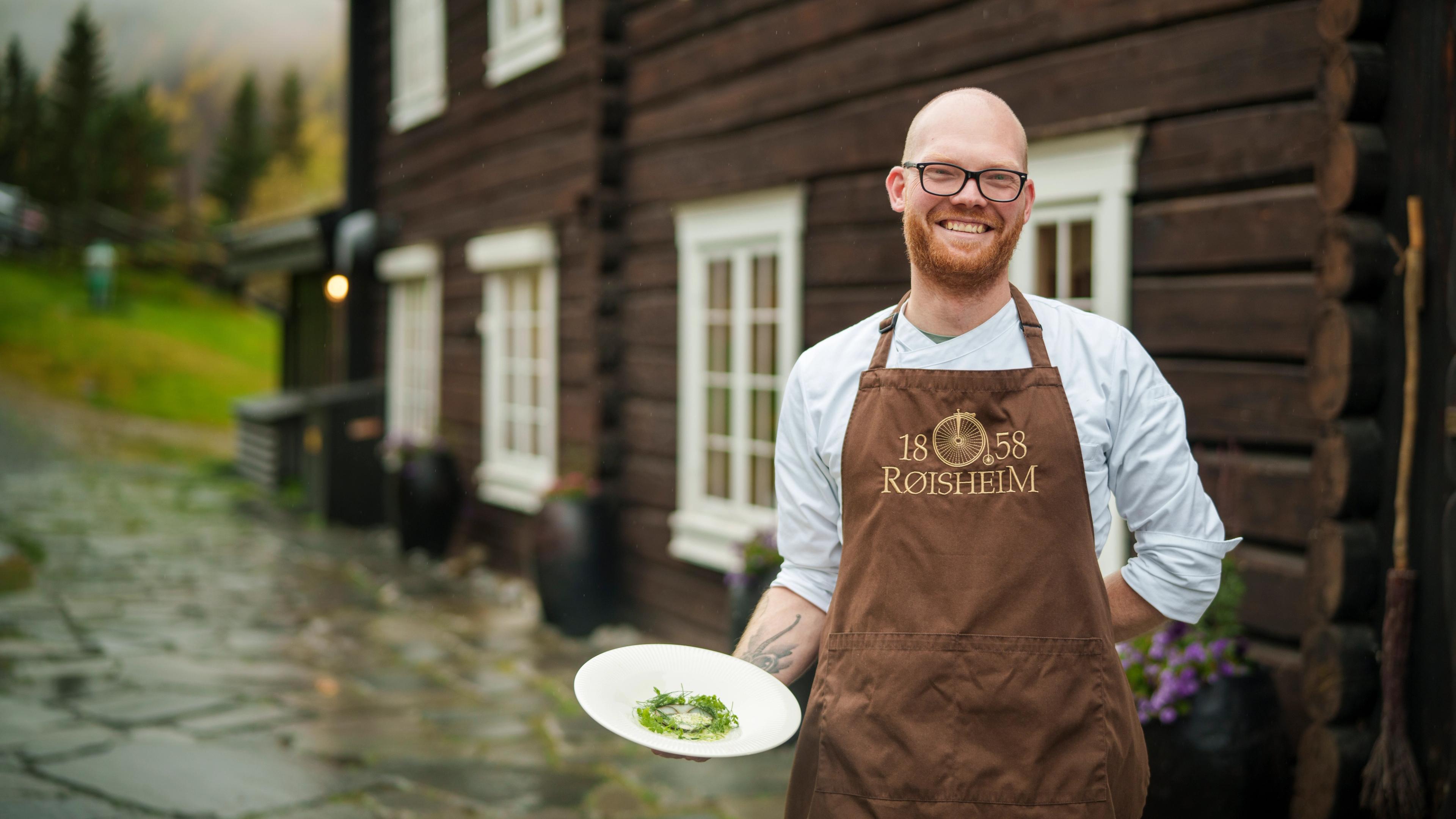 A chef is holding a dish outside of Røisheim Hotell