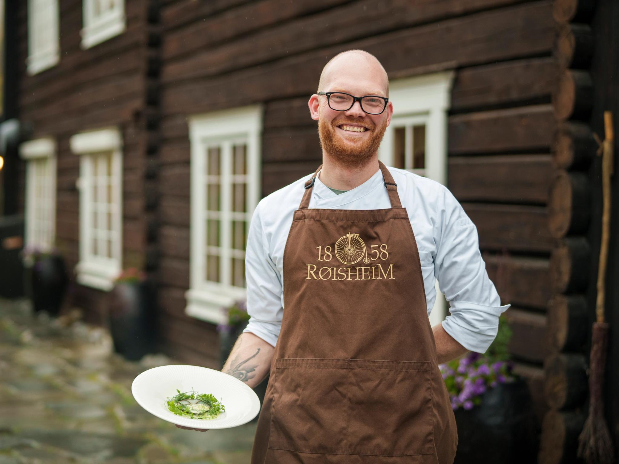 A chef is holding a dish outside of Røisheim Hotell