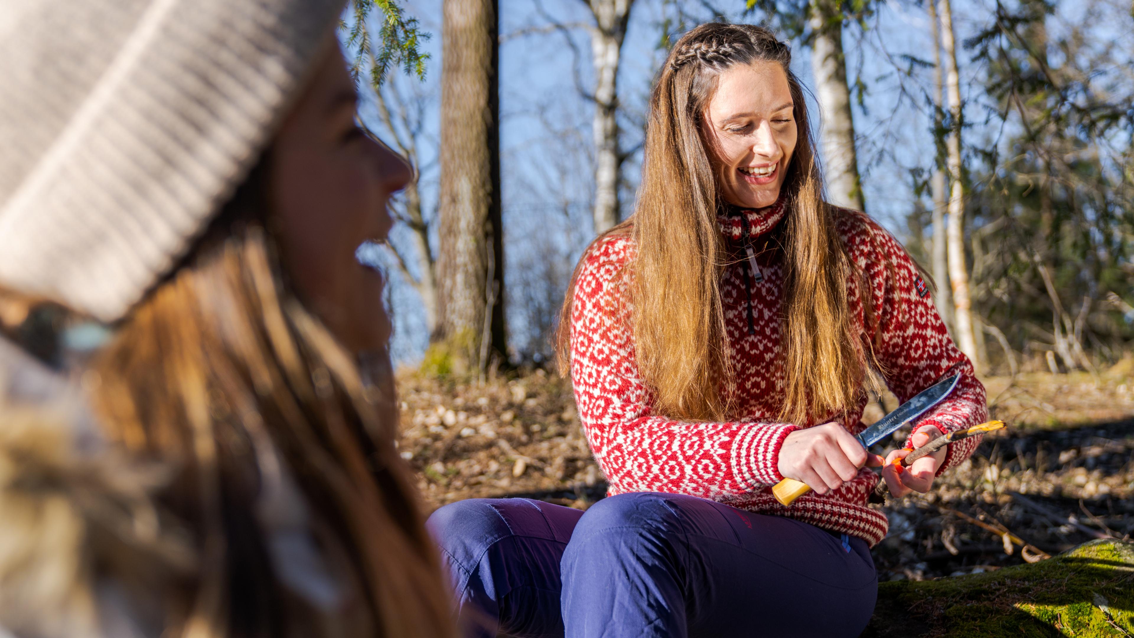 A girl whittle a stick in the woods