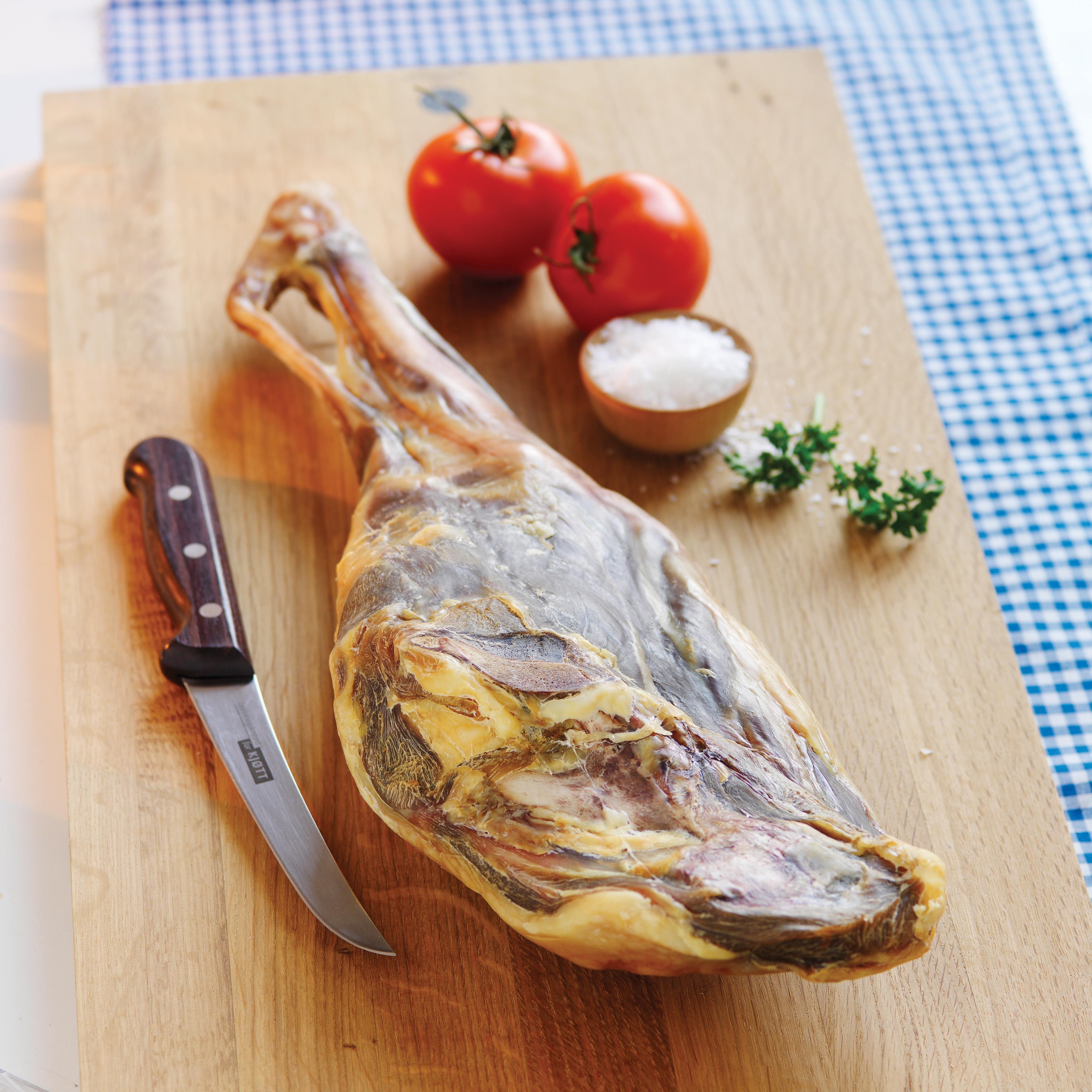Fenalår on a cutting board with salt and tomatos