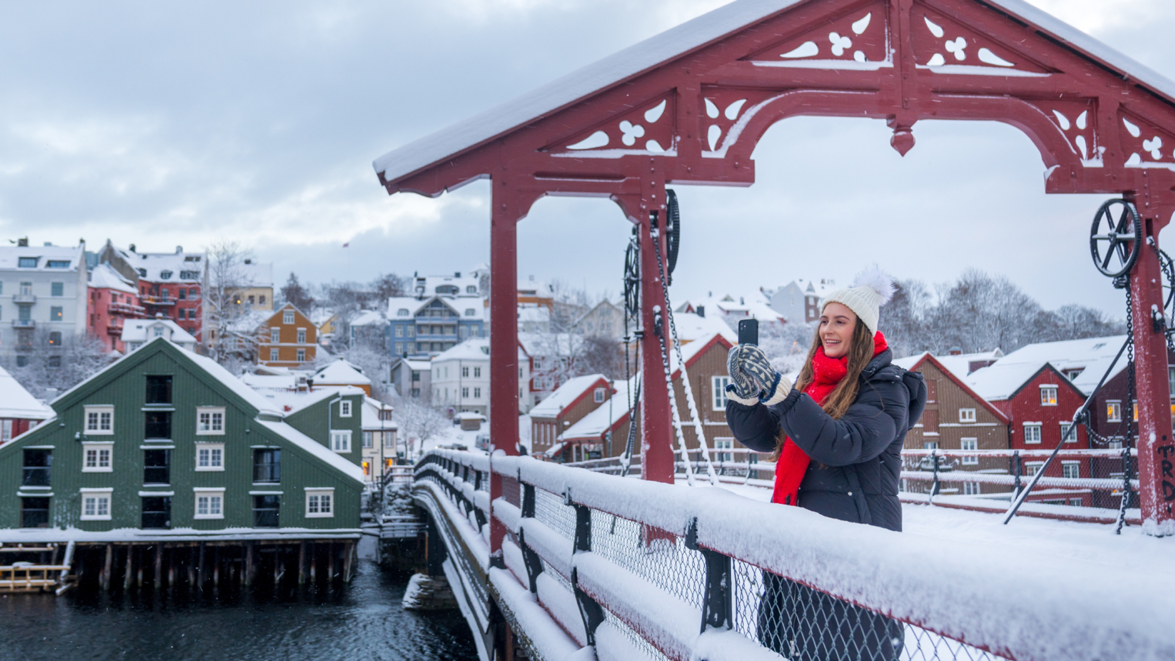 A women taking a picture from the Old Town Bridge in Trondheim in winter, Trøndelag, Norway.