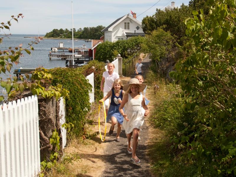 En gruppe børn løber langs et hvidt stakit på Merdø i Sørlandet