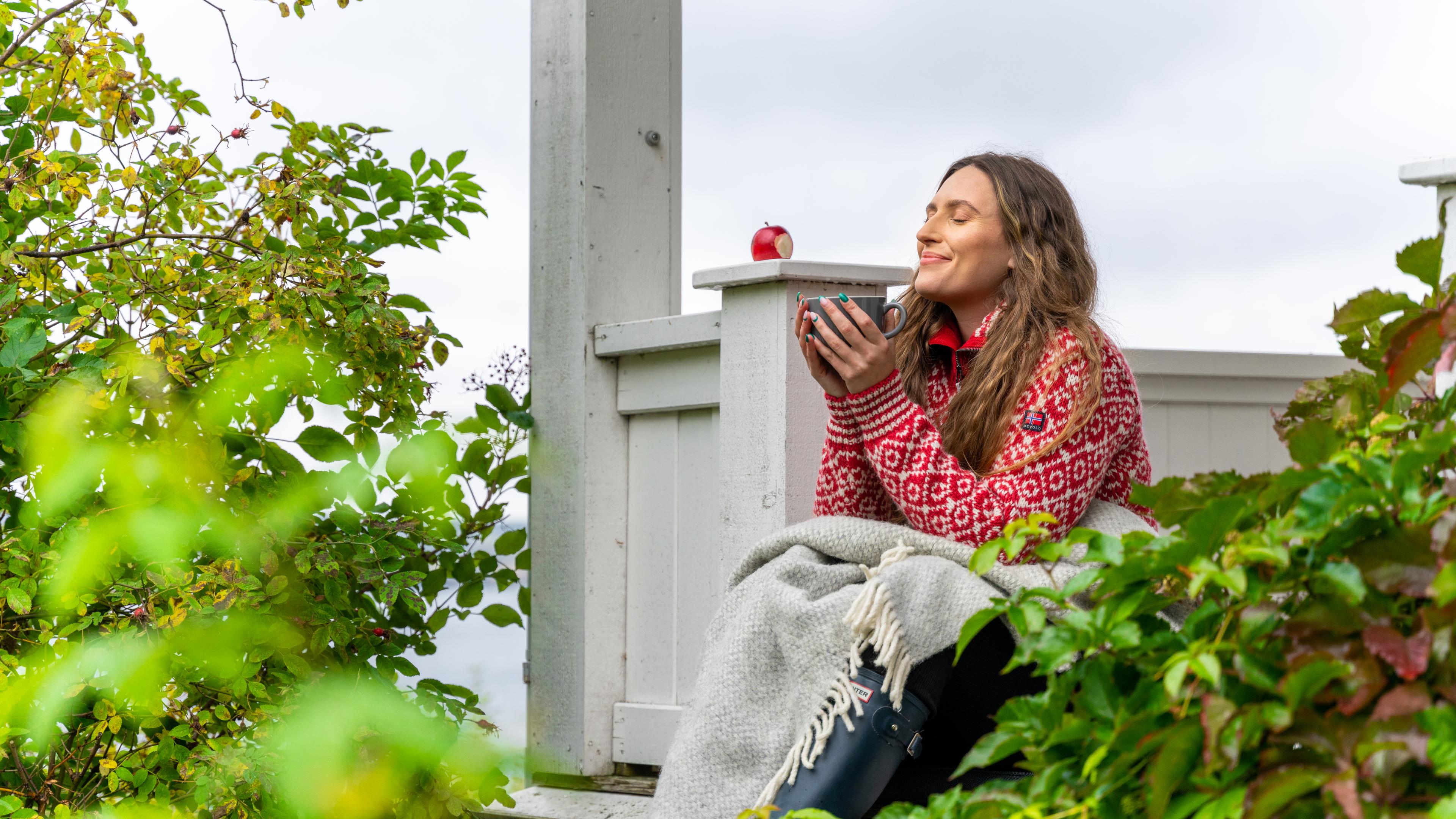 A woman having a good time in the garden at the farm Hoel Gård at Nes, Eastern Norway.