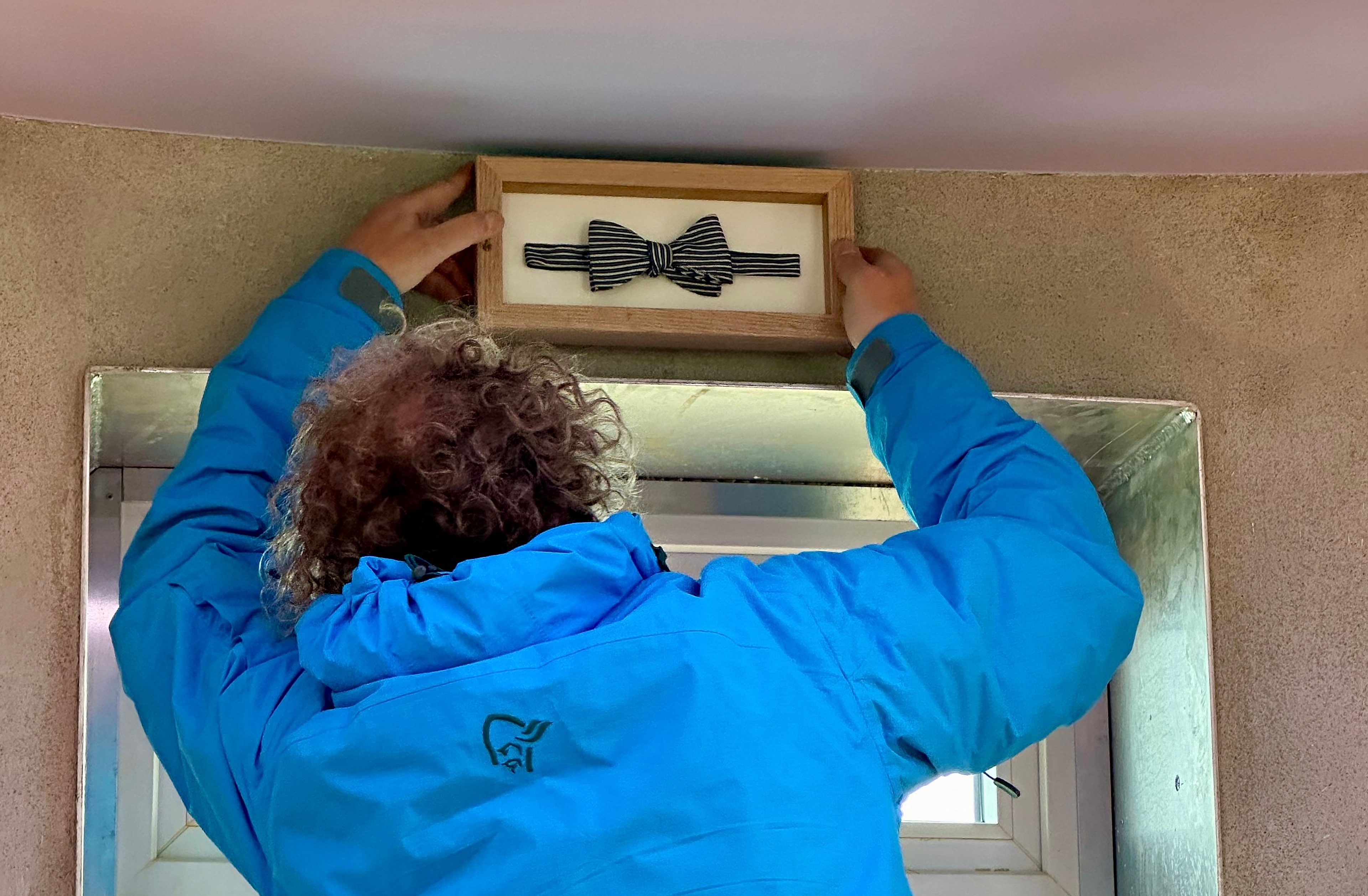 Martin Otterbeck putting up a Per Fugelli's bow tie on the wall inside Ettertanken at Røst