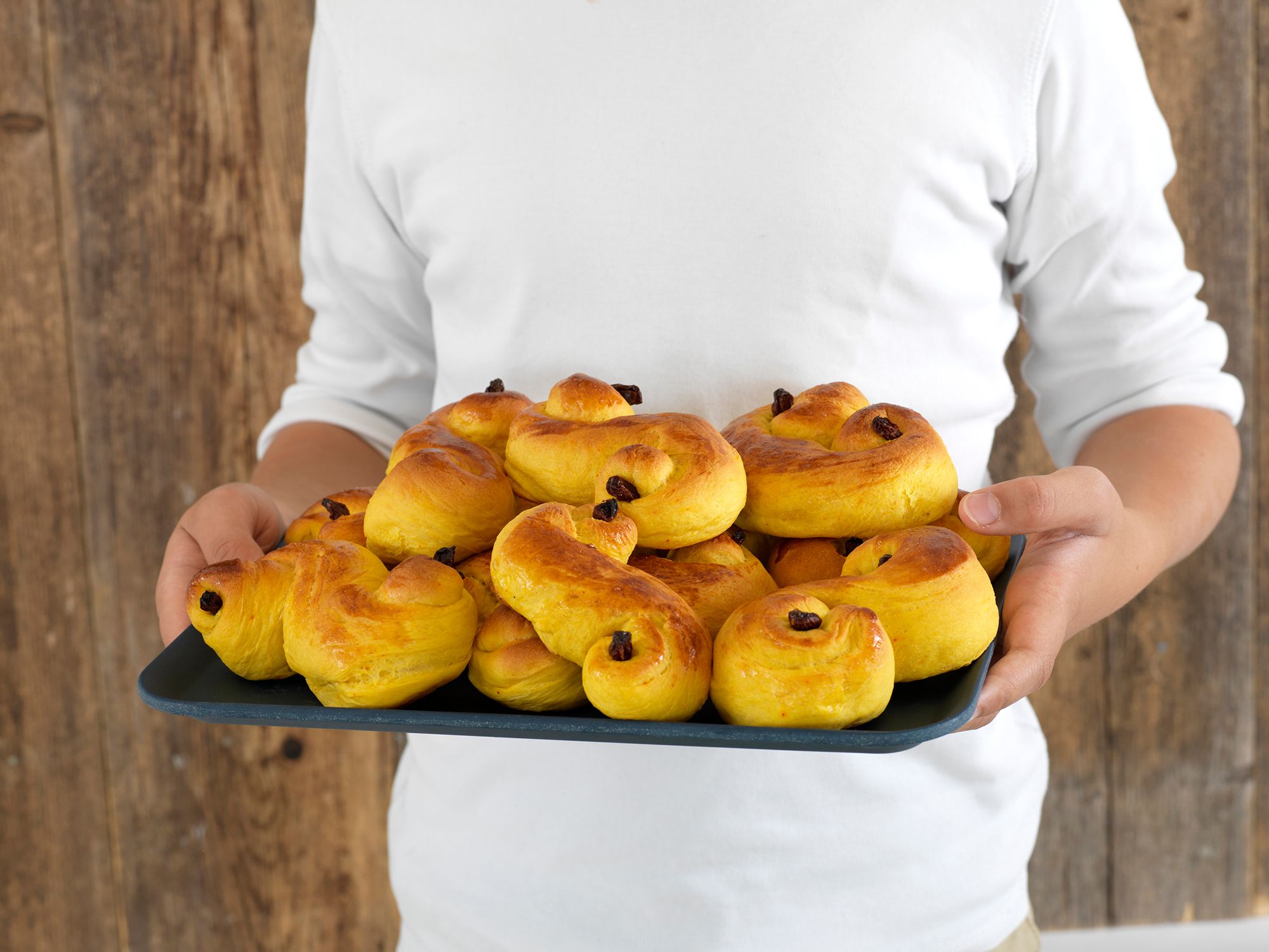 A person holding a plate with saffron buns in Norway