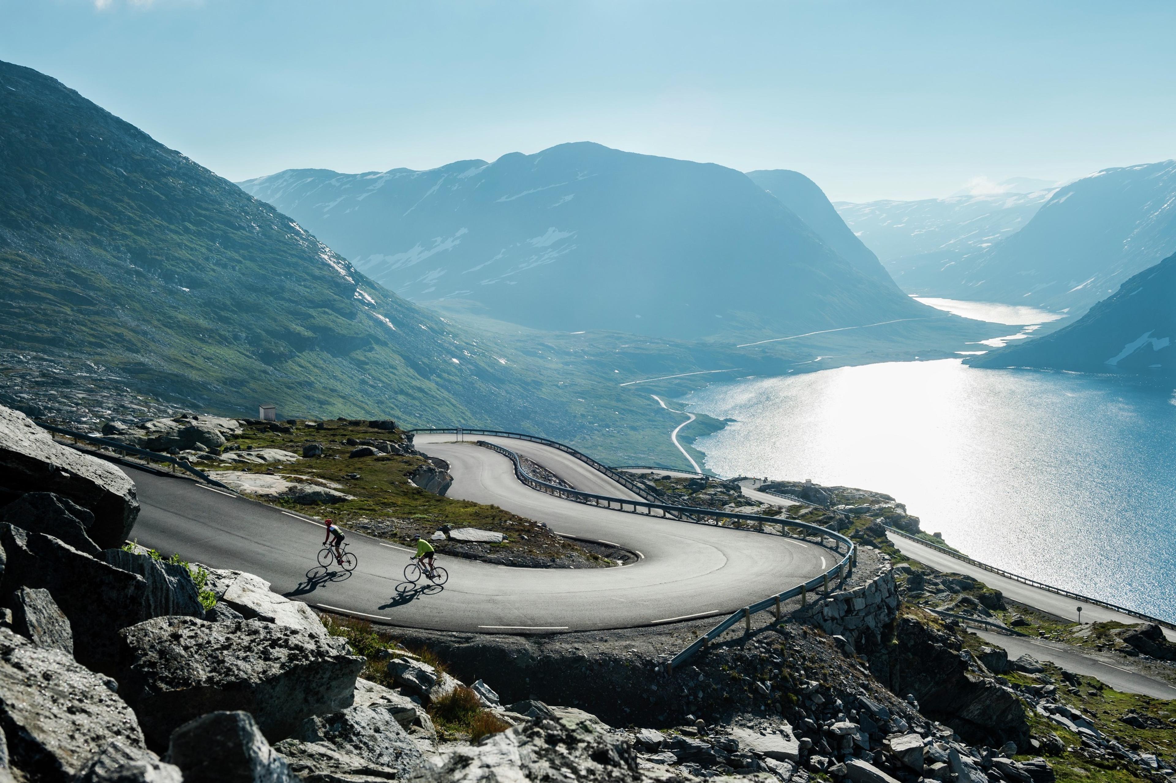 Two people road cycling up a winding road above the Geirangerfjord in Fjord Norway