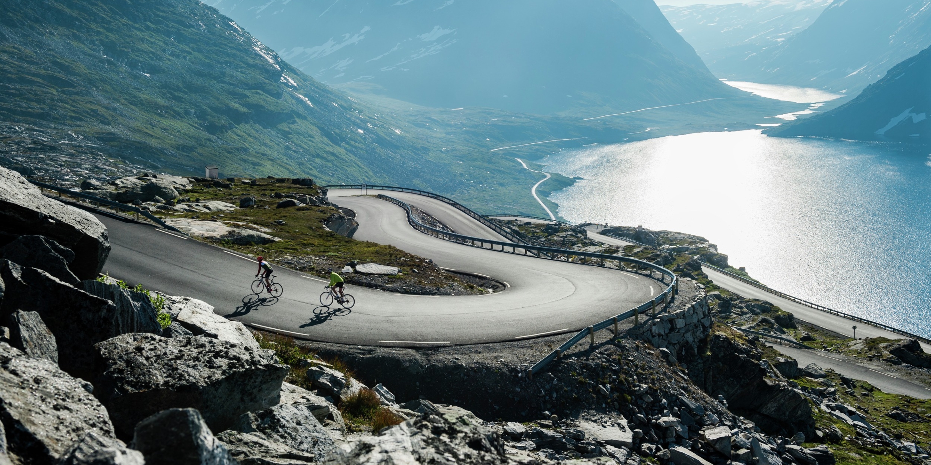 Two people road cycling up a winding road above the Geirangerfjord in Fjord Norway