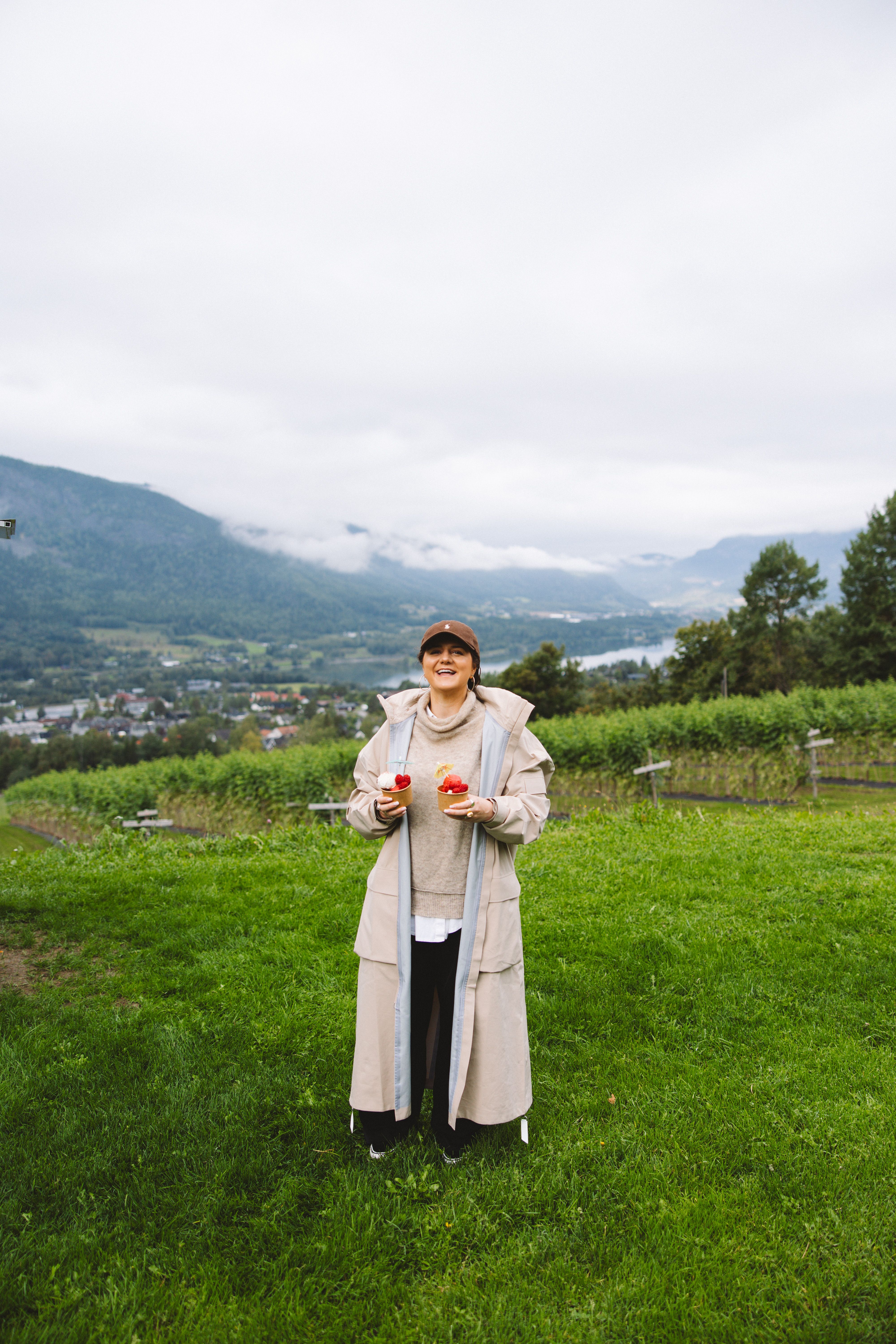 A woman holding raspberries in a field.