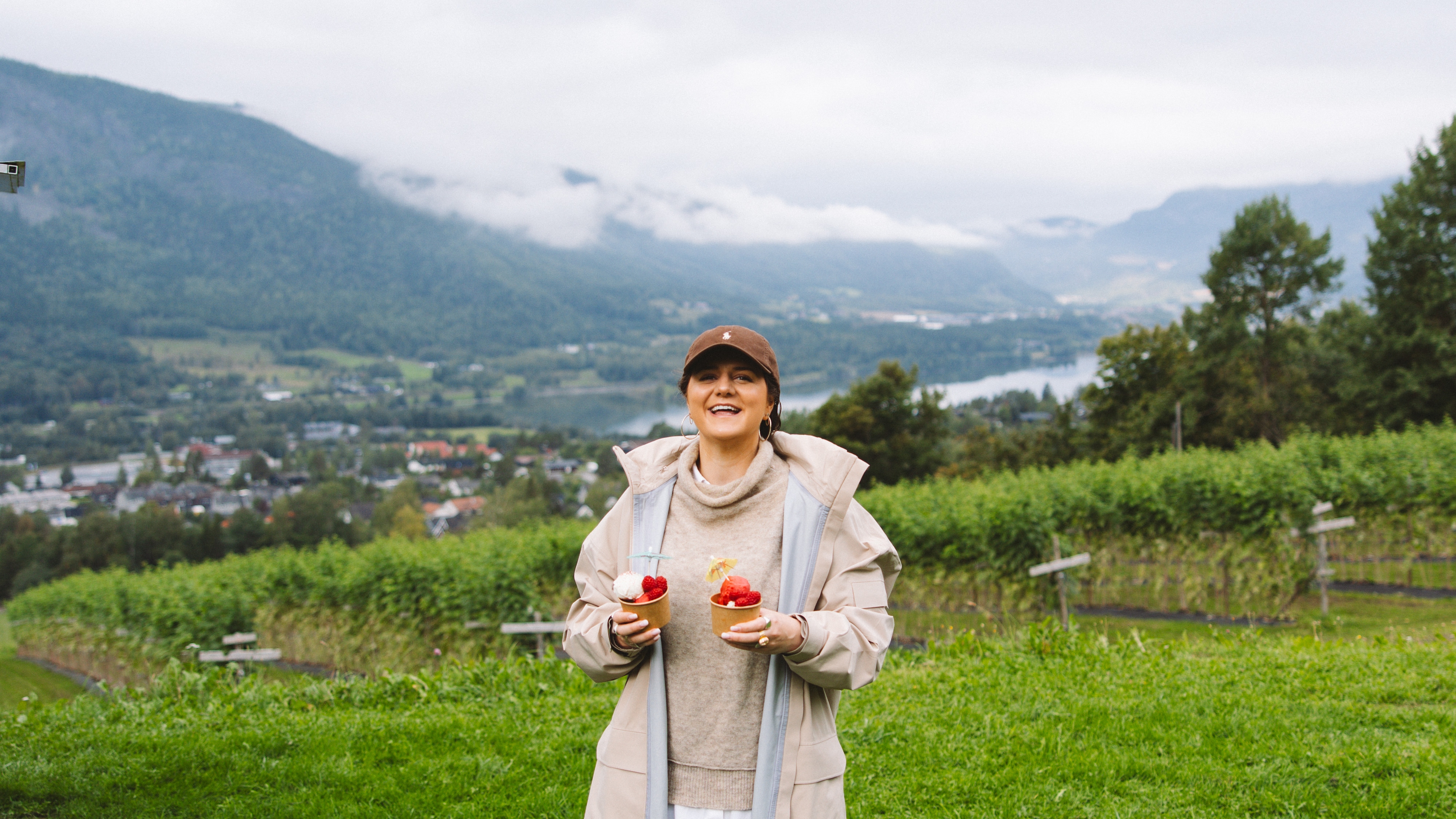 A woman holding raspberries in a field.