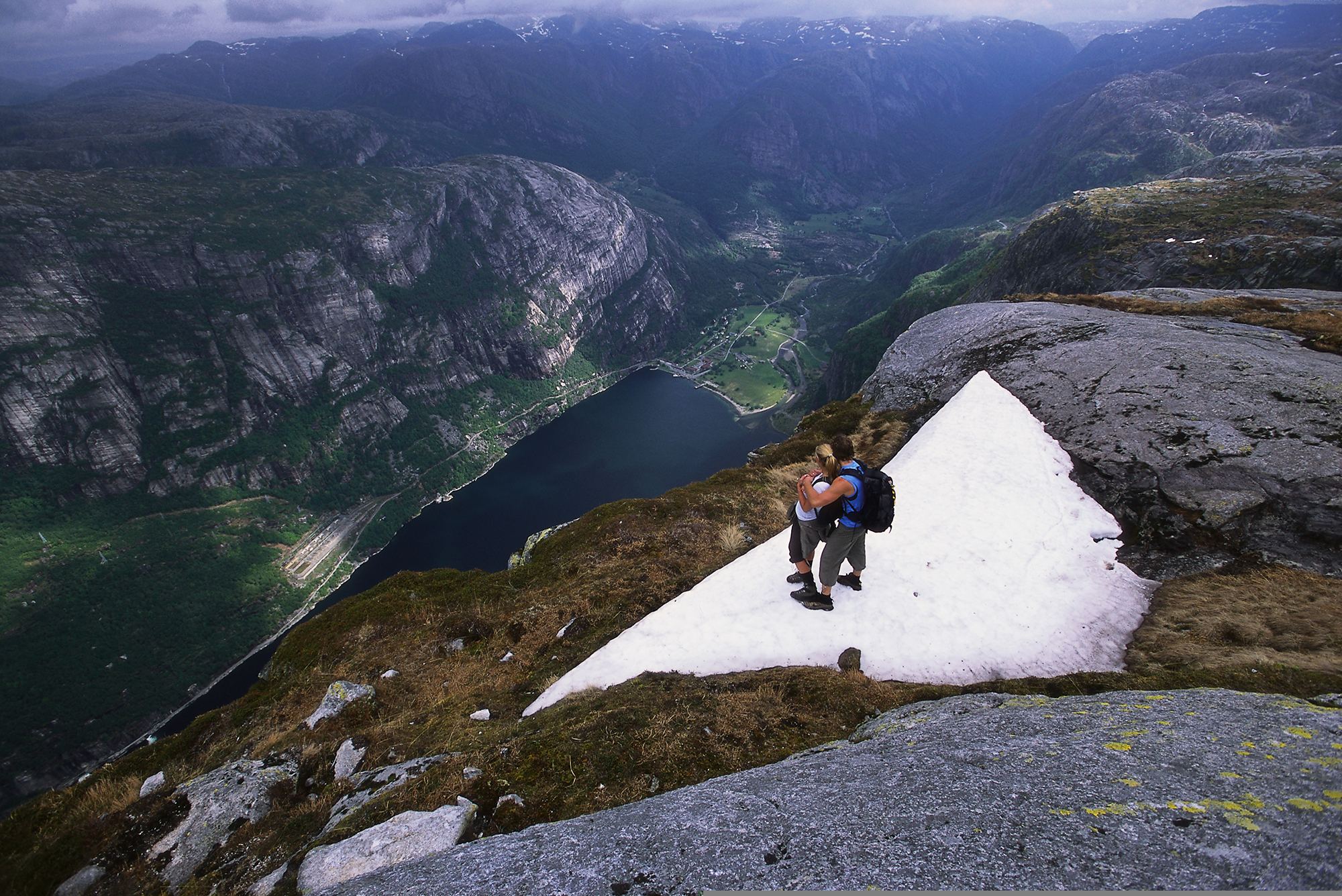 Couple on Mount Kjerag in Fjord Norway admiring view of the Lysefjord