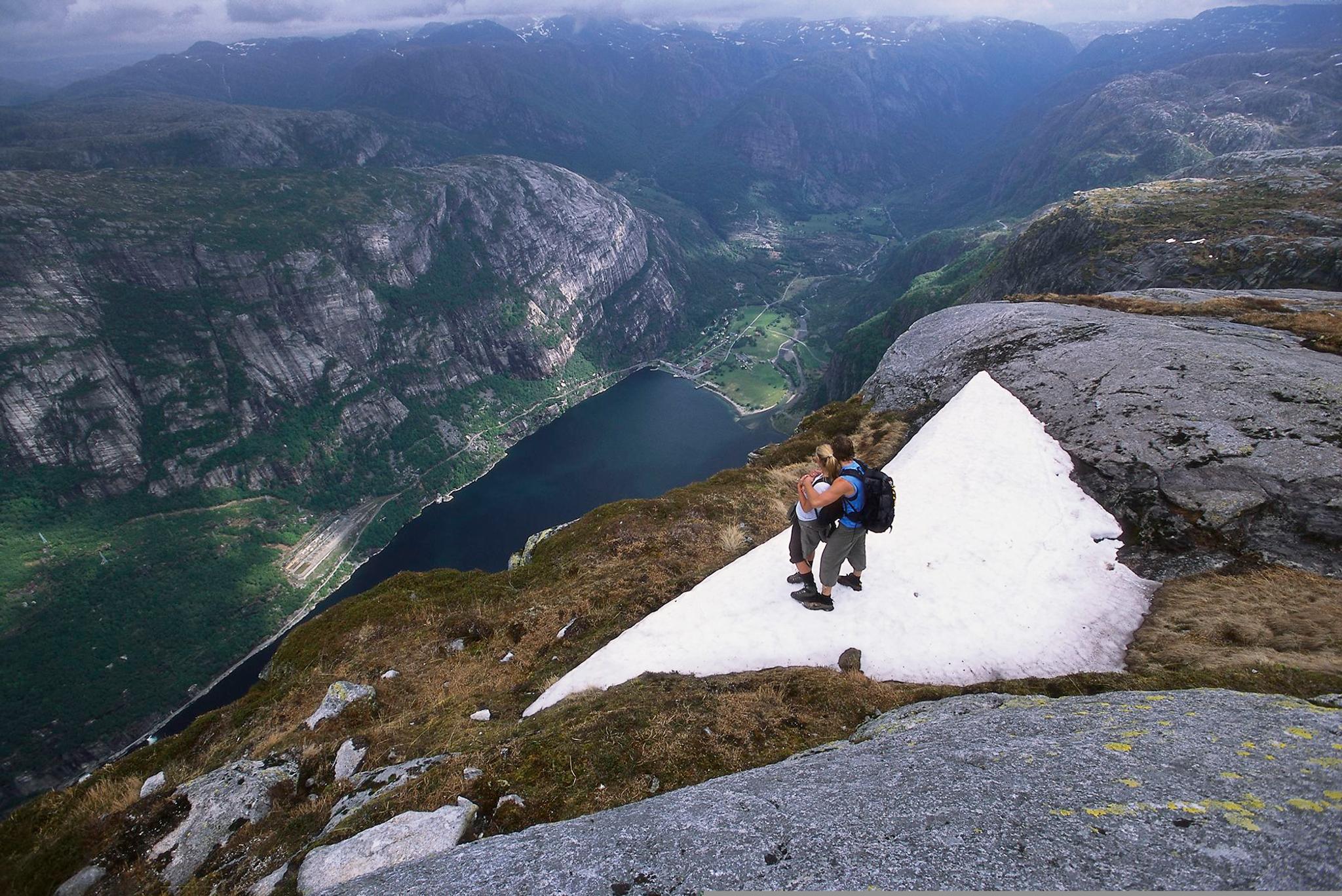 Couple on Mount Kjerag in Fjord Norway admiring view of the Lysefjord