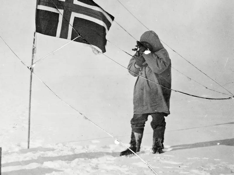 Roald Amundsen and Helmer Hanssen next to a Norwegian flag at the South Pole in 1911