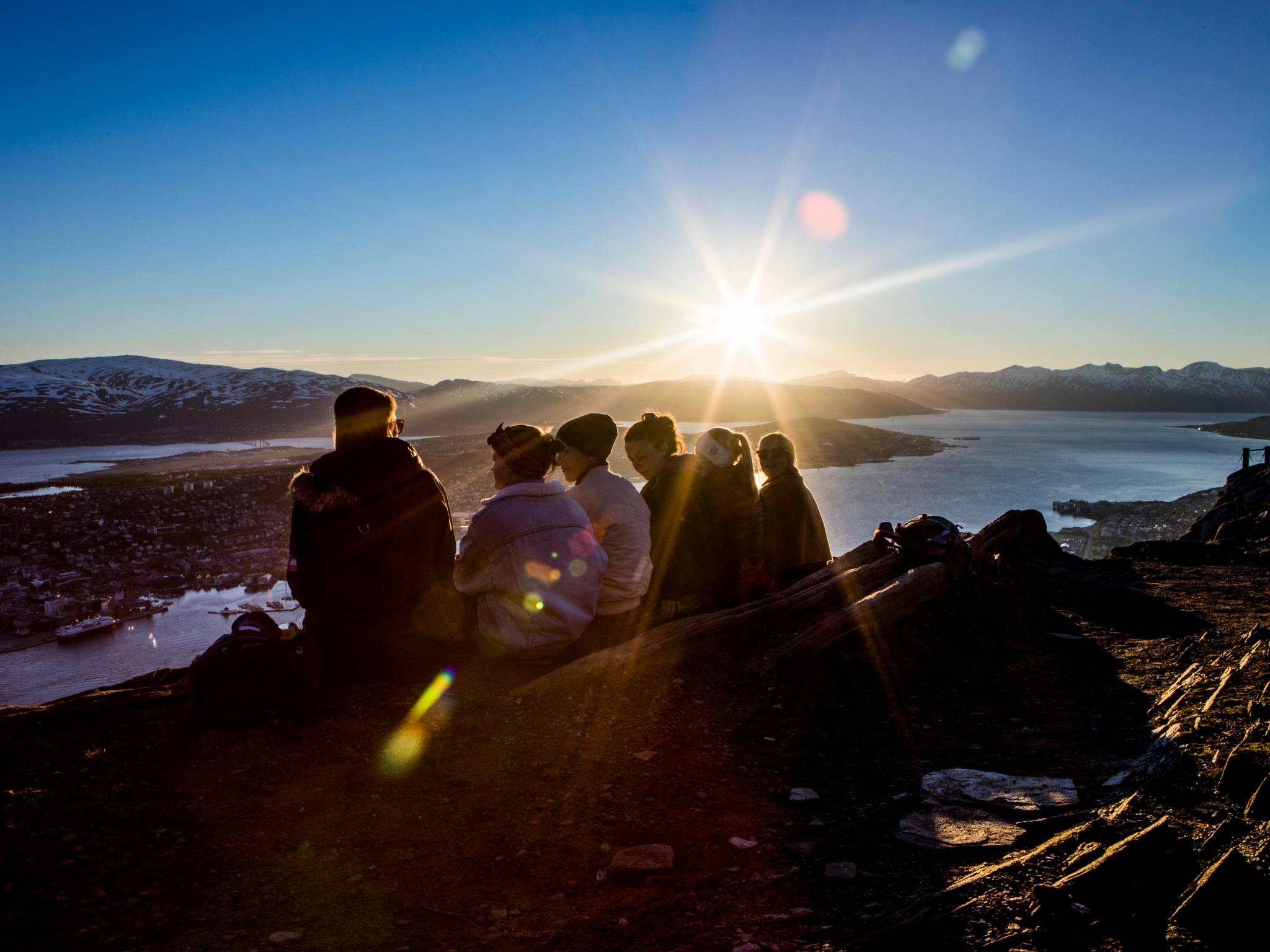 People enjoying the midnight sun from the top of a mountain
