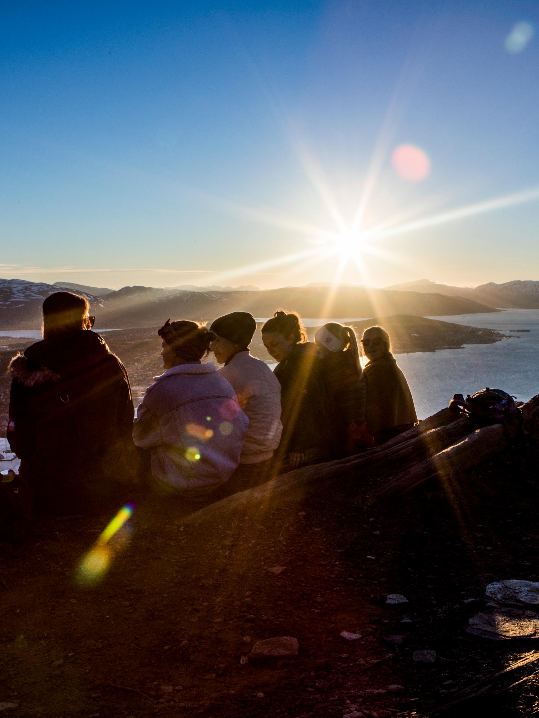 People enjoying the midnight sun from the top of a mountain