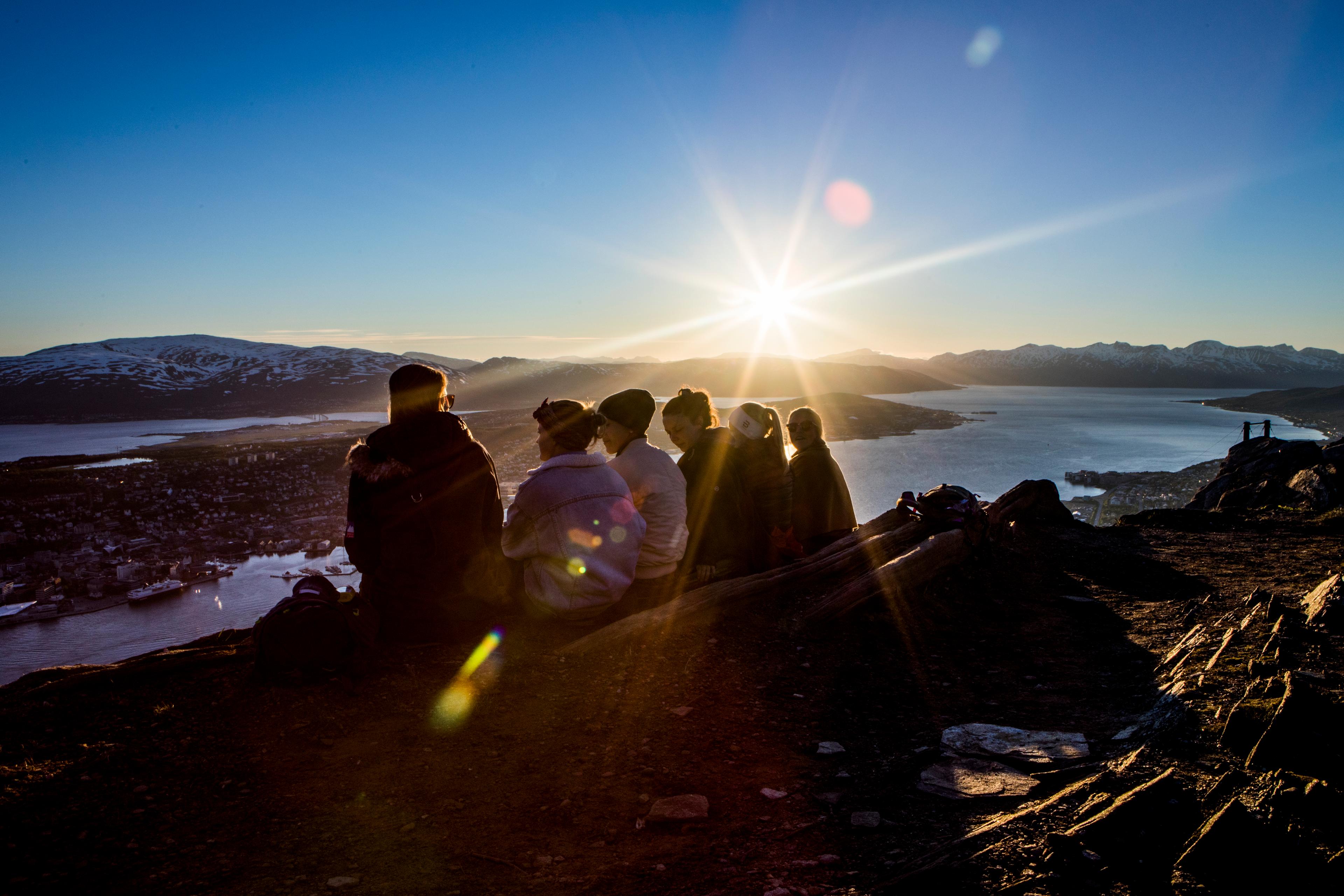 People enjoying the midnight sun from the top of a mountain