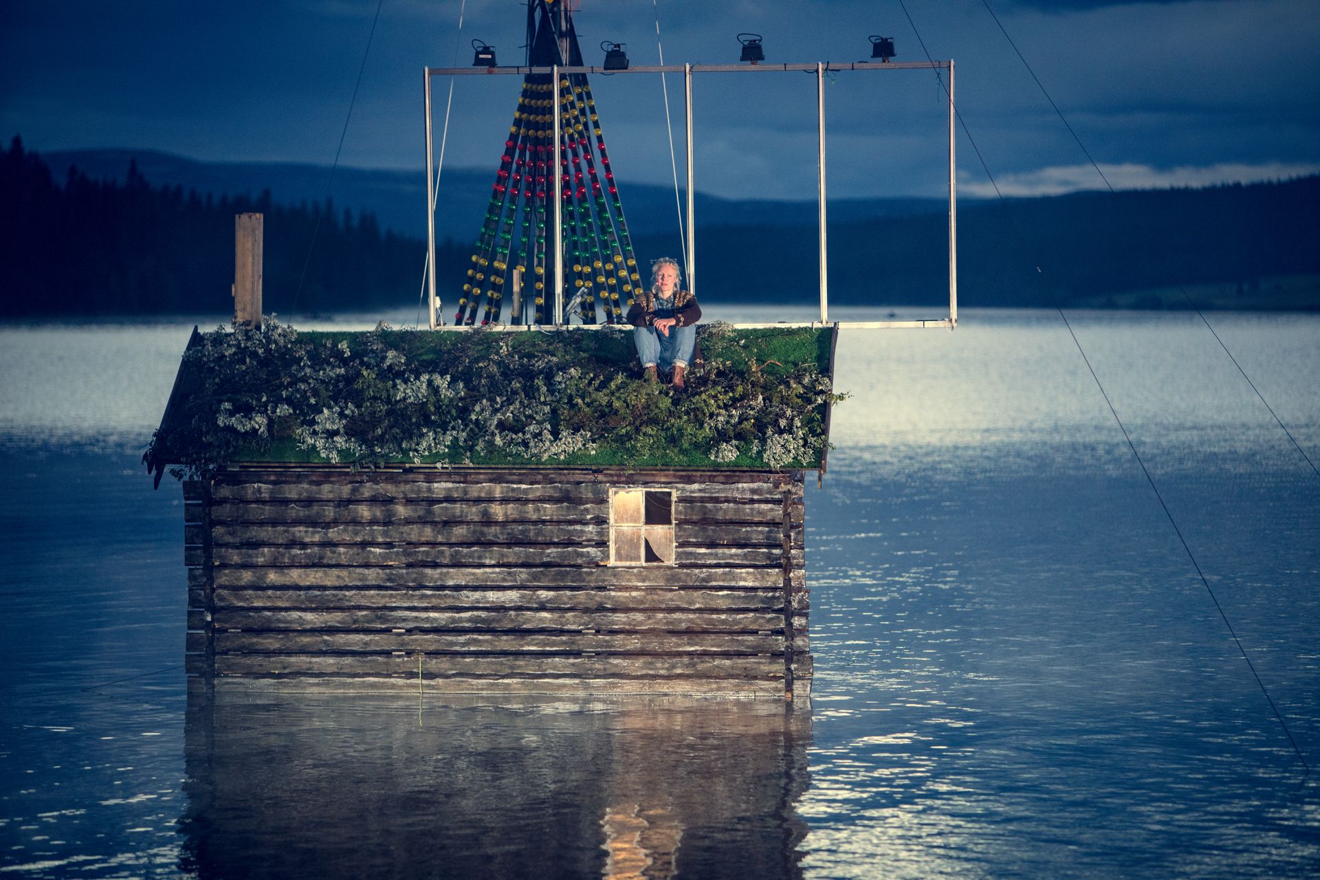 An actor sitting on the roof of a cabin in the water, Peer Gynt Festival, Gålå, Eastern Norway