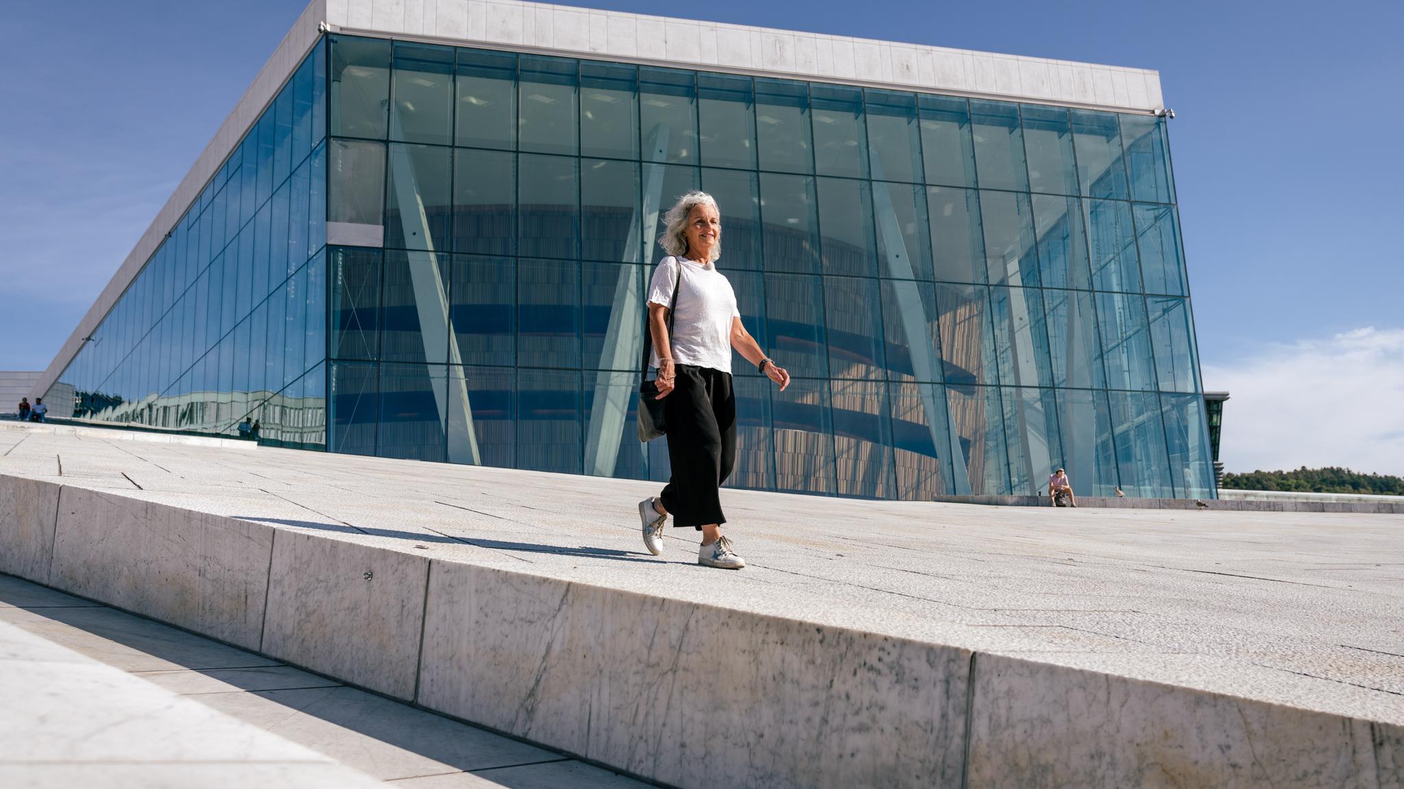 A woman walking over Oslo Opera House