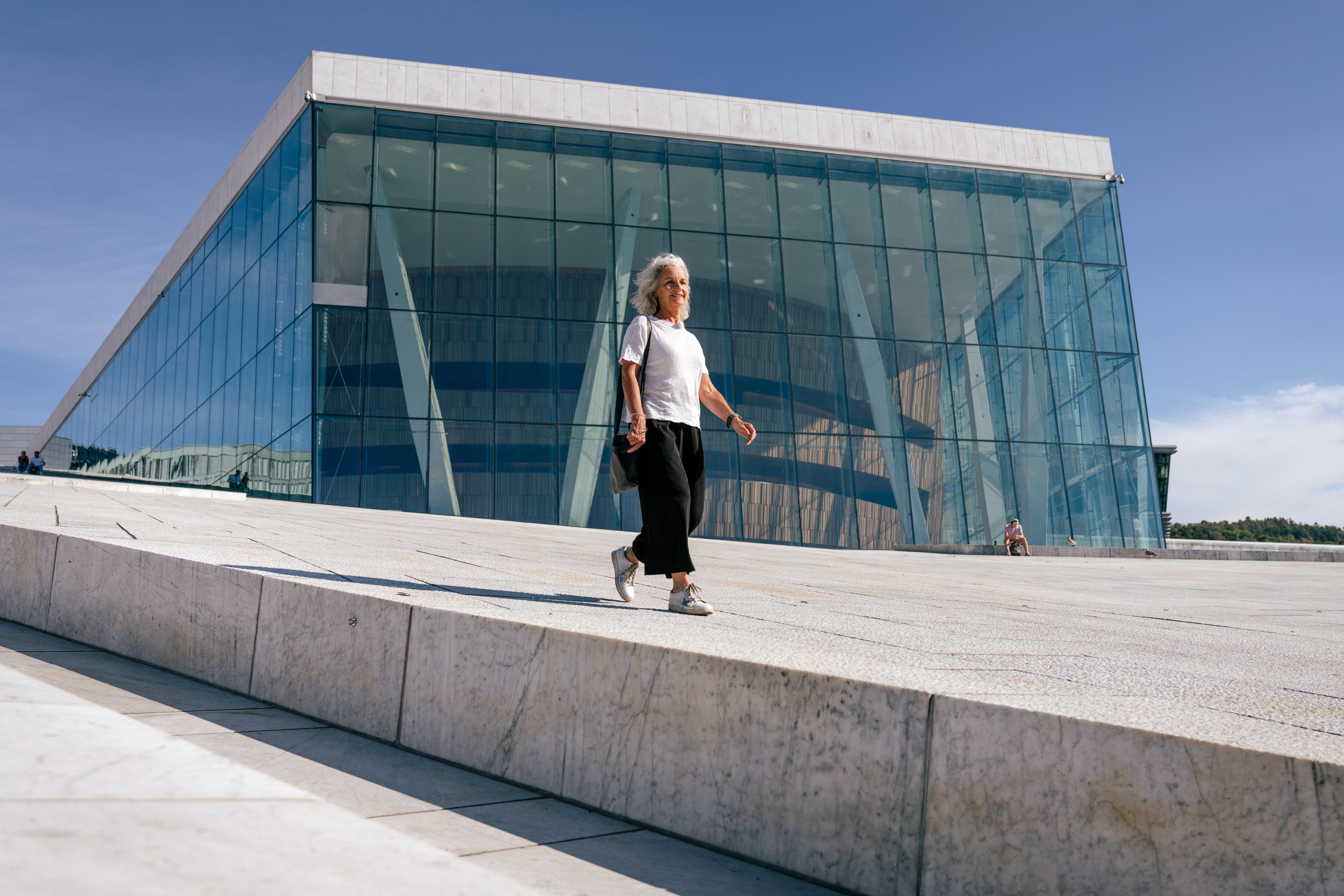 A woman walking over Oslo Opera House
