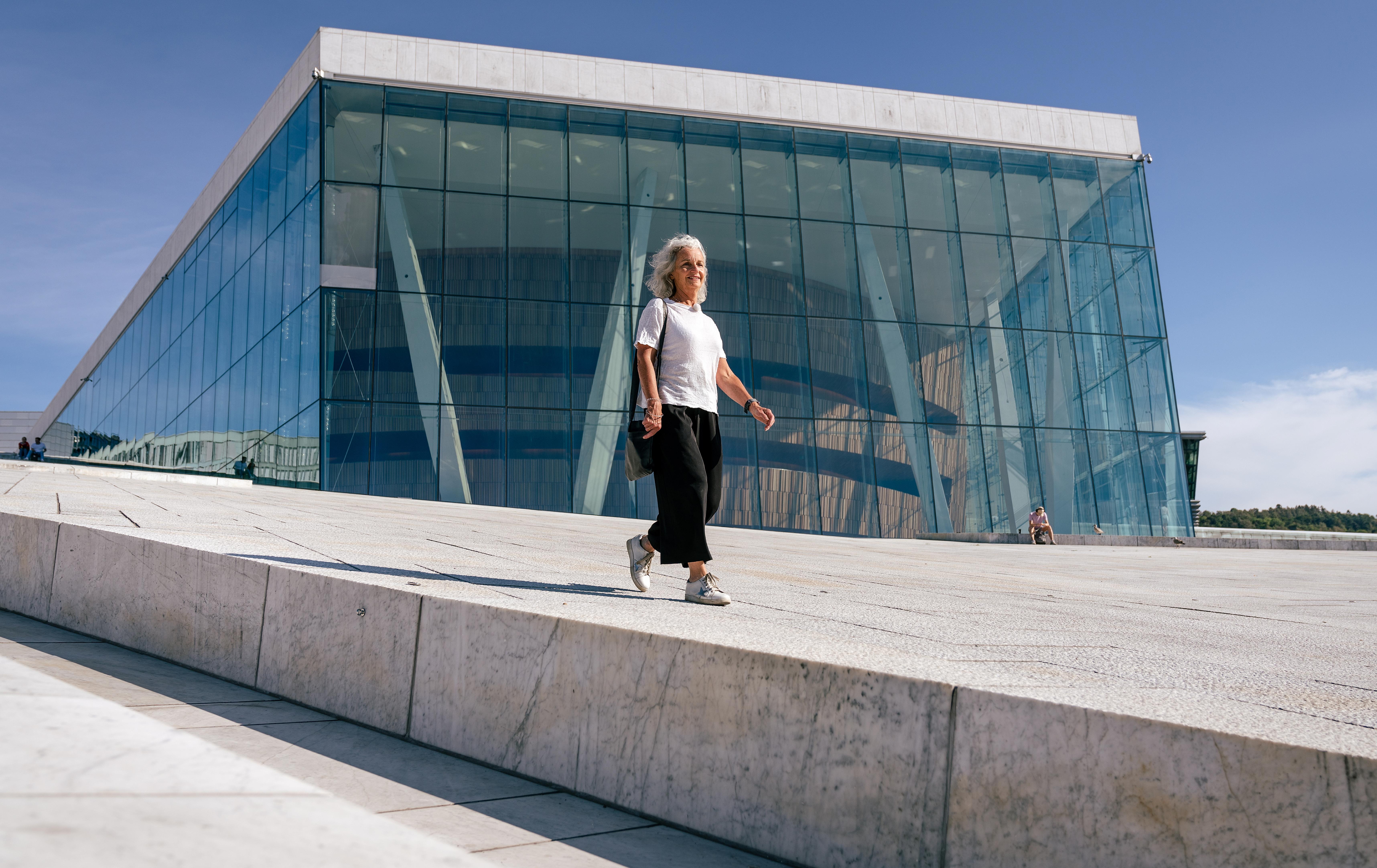A woman walking over Oslo Opera House