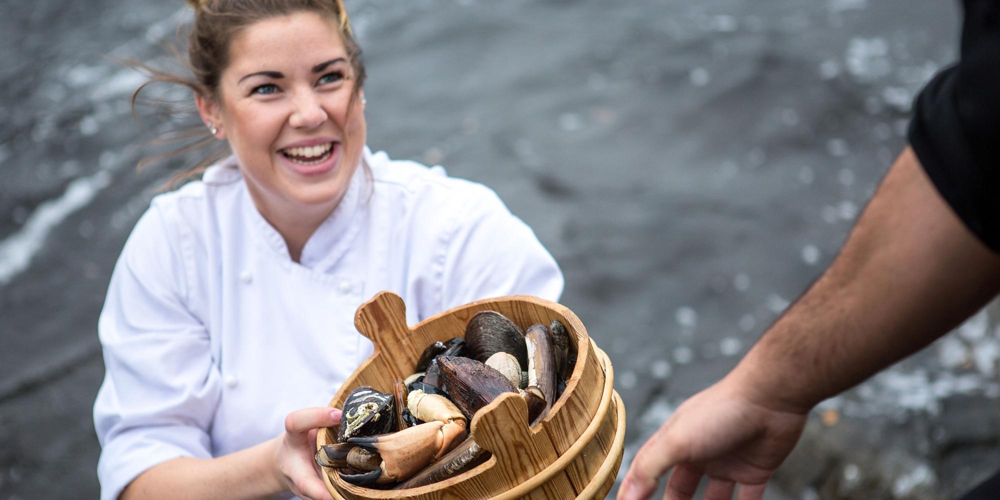 A renowned chef holding a bucket of fresh seafood from Fosen in Trøndelag