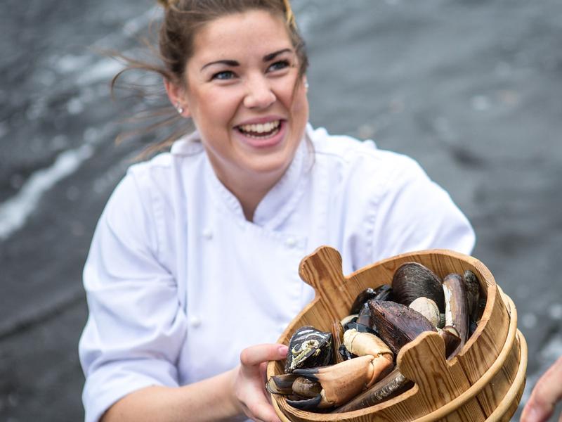 A renowned chef holding a bucket of fresh seafood from Fosen in Trøndelag