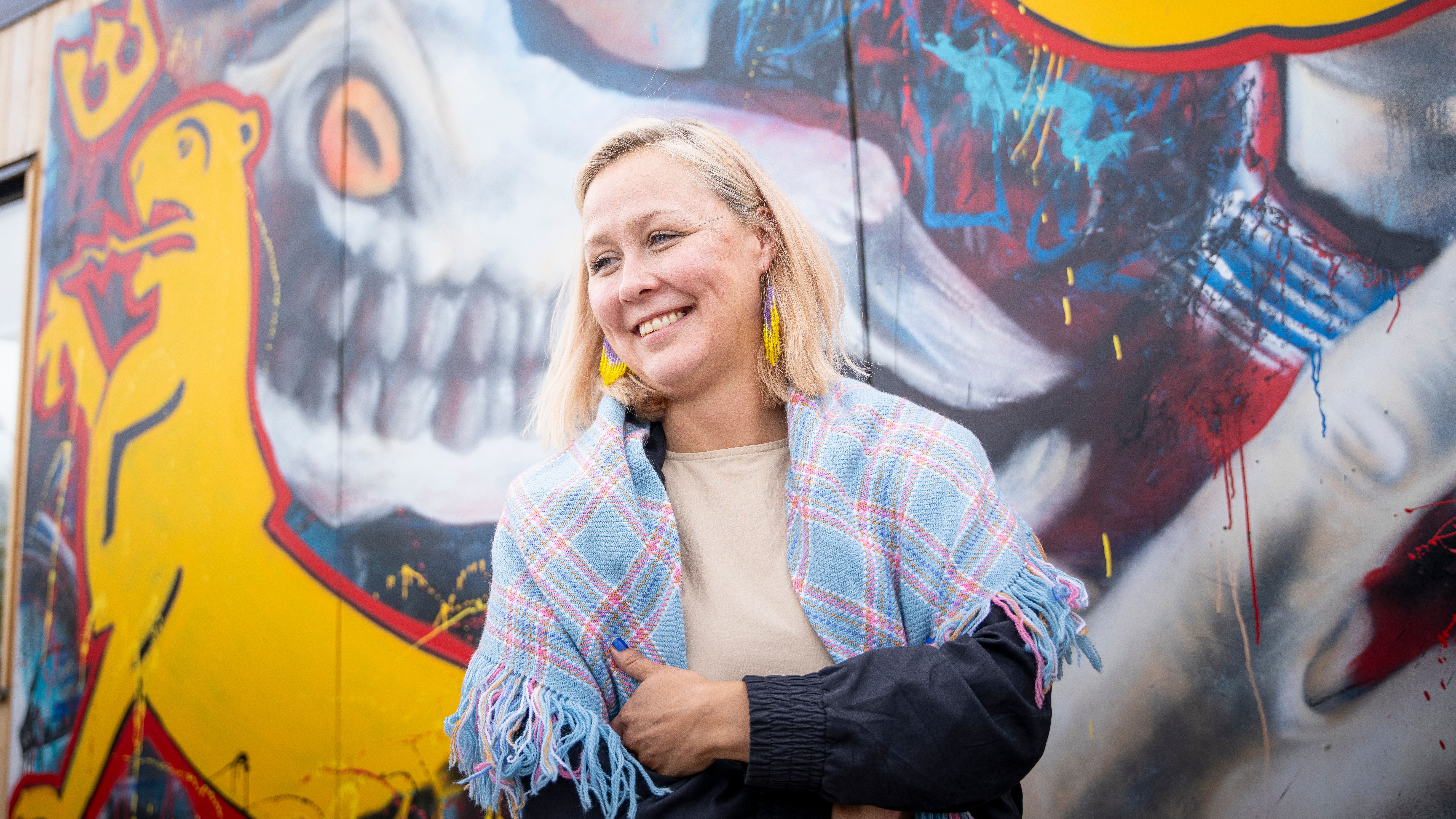 Portrait of Dine Arnannguaq Fenger Lynge in front of modern Sami art.