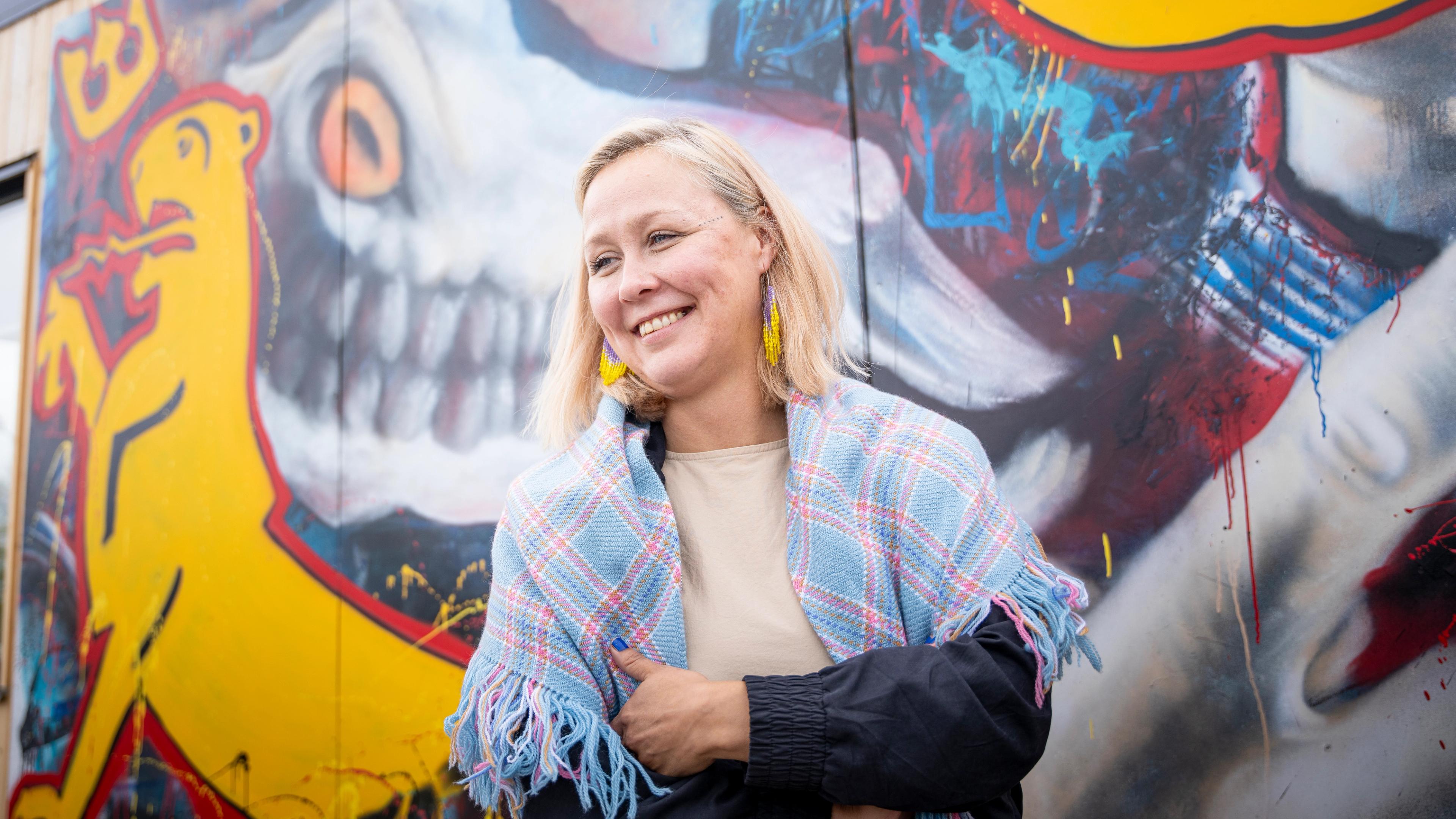 Portrait of Dine Arnannguaq Fenger Lynge in front of modern Sami art.