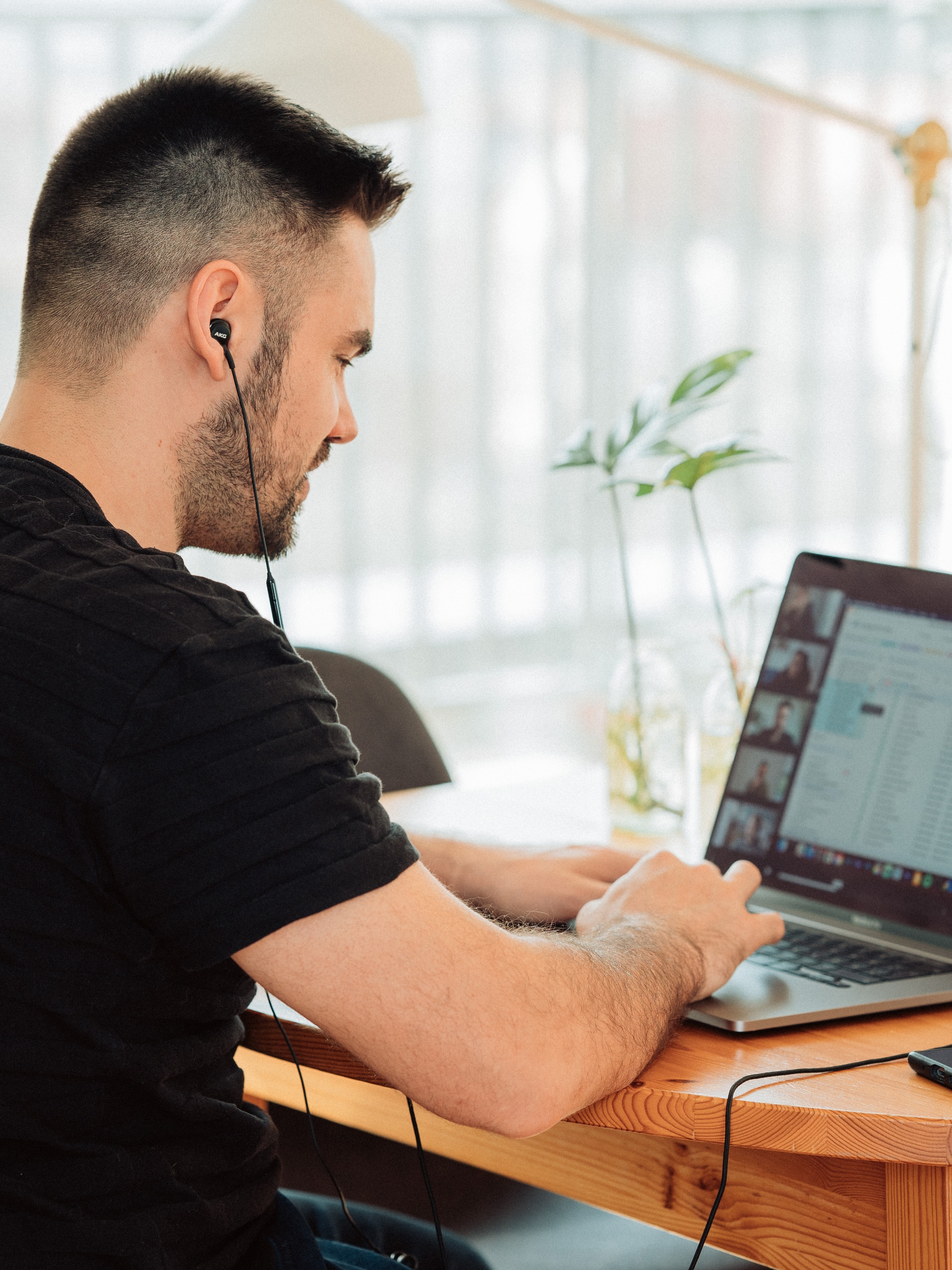 A young man in a black T-shirt in a conference meeting on his laptop